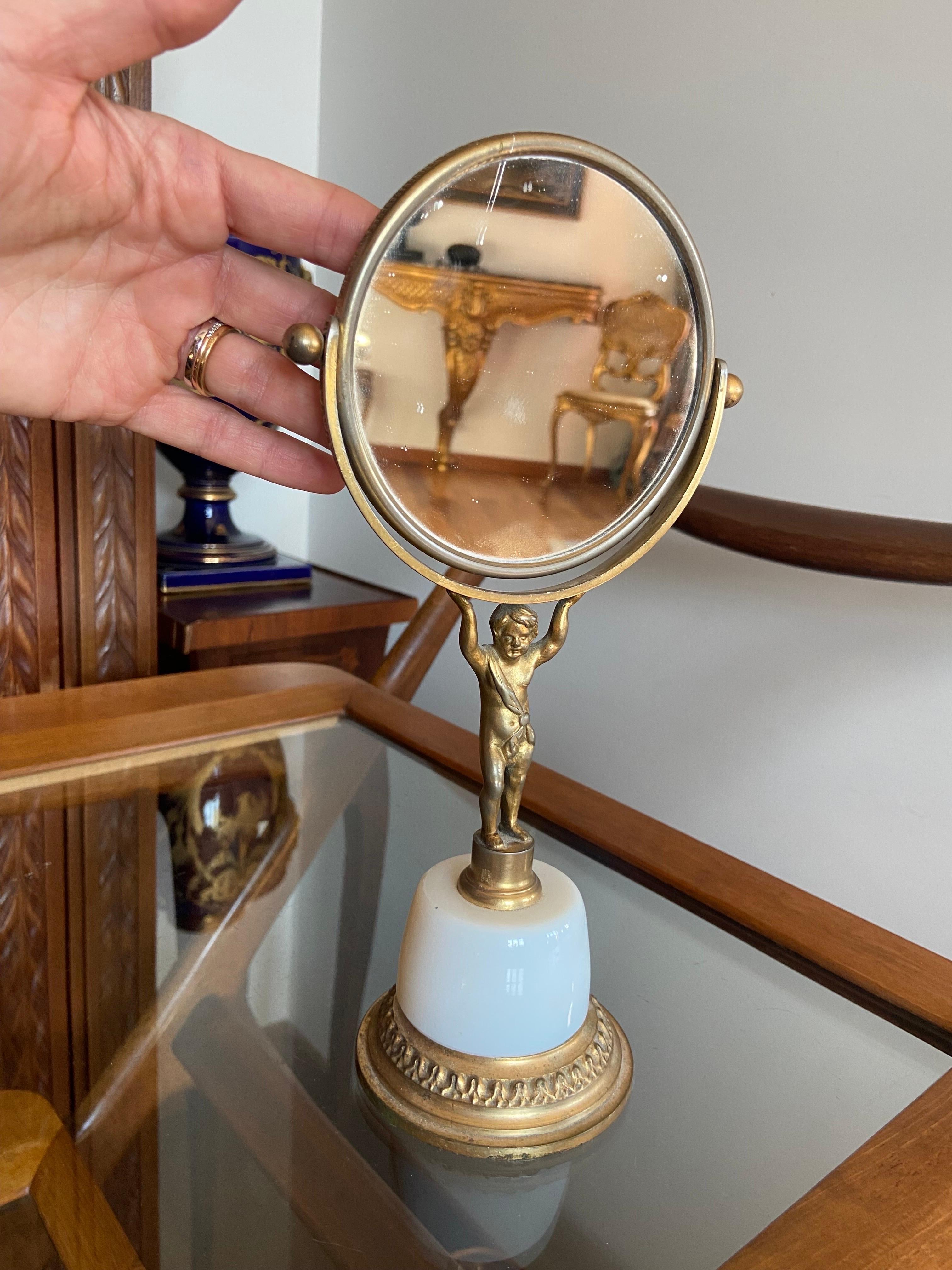 20th century gilded bronze double side table mirror decorated with a figure of a boy holding the mirror, which is resting on opaline base.
France, circa 1930.