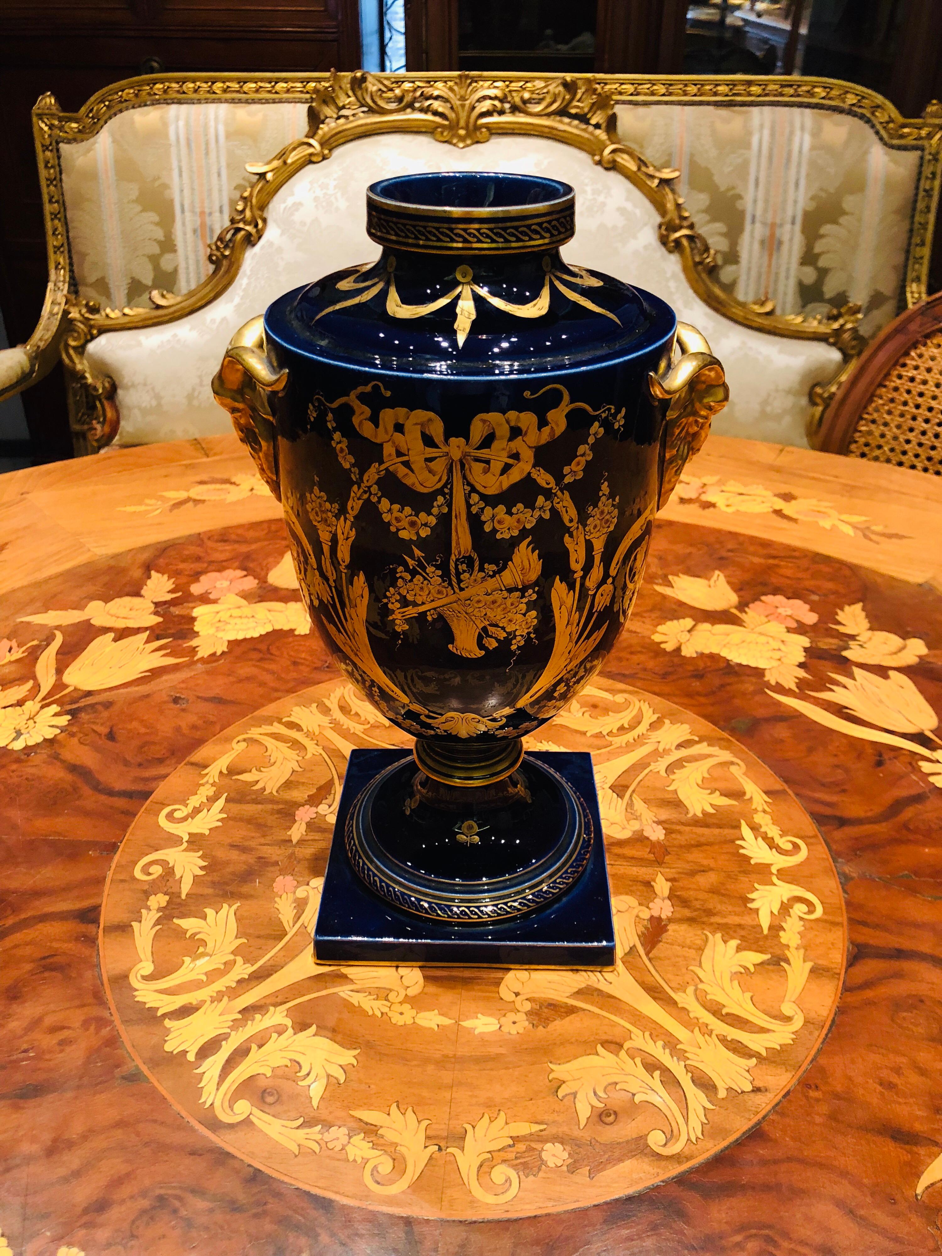 Amphora-shaped vase and in the Empire style, circa 1920, France made of earthenware with a marine-blue background with gold decorations in the spirit of Sèvres. Round neck surrounded by gold, and frieze inlays, recalling the main theme. Also gilded