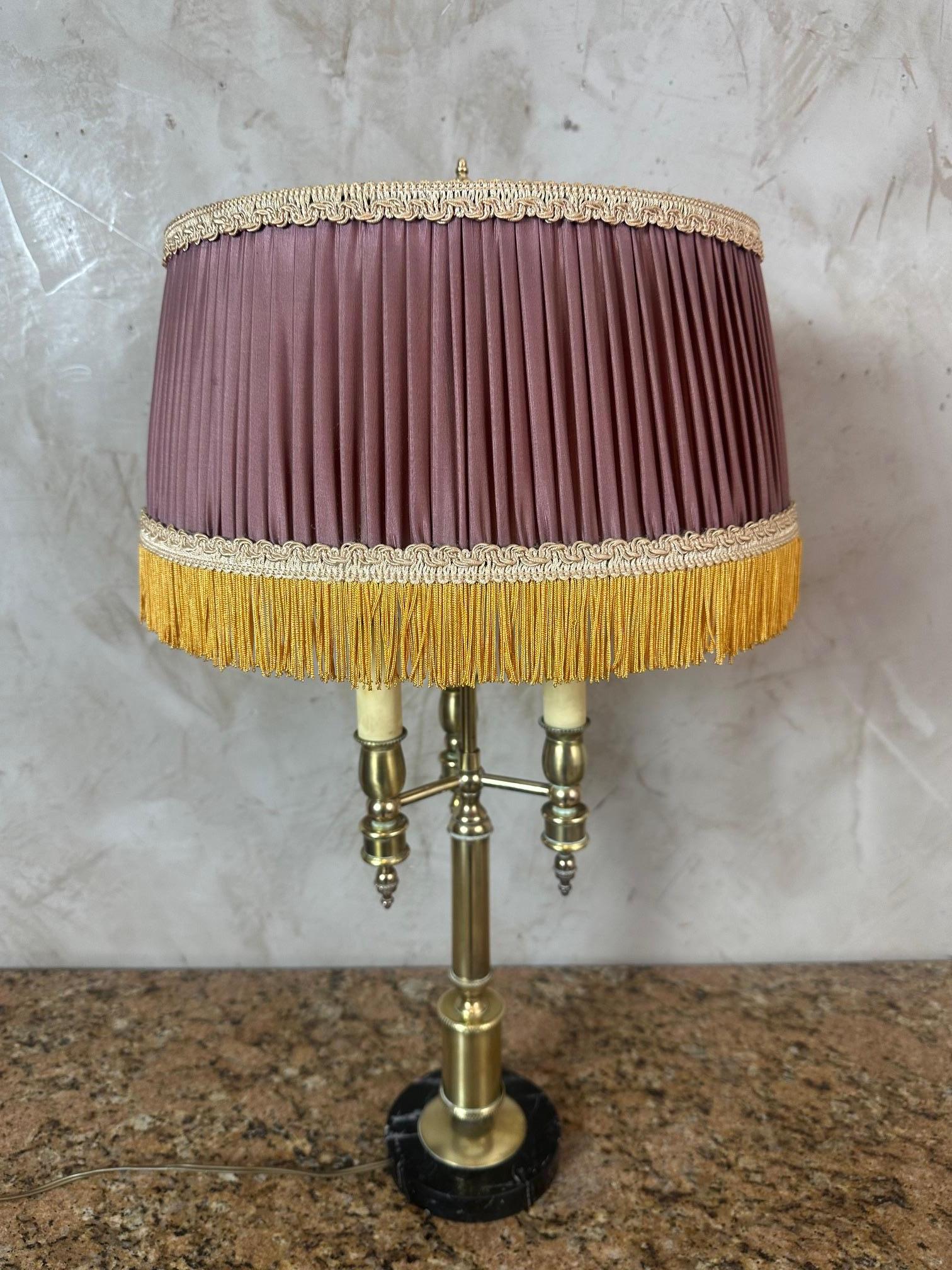 Esta elegante lámpara de estilo Imperio, de la década de 1950, presenta una refinada base de latón dorado de silueta atemporal, asentada sobre un pedestal de mármol negro en contraste que le añade carácter y estabilidad.

La lámpara está coronada