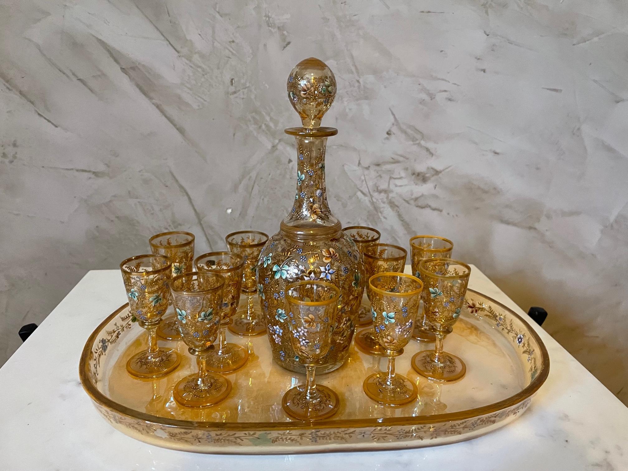Very nice and rare enameled glass service from the 1900s, a tray, a carafe with a plug and 12 liquor glasses. 
Beautiful amber color with golden and blue flower decoration. 
Very good quality and condition.