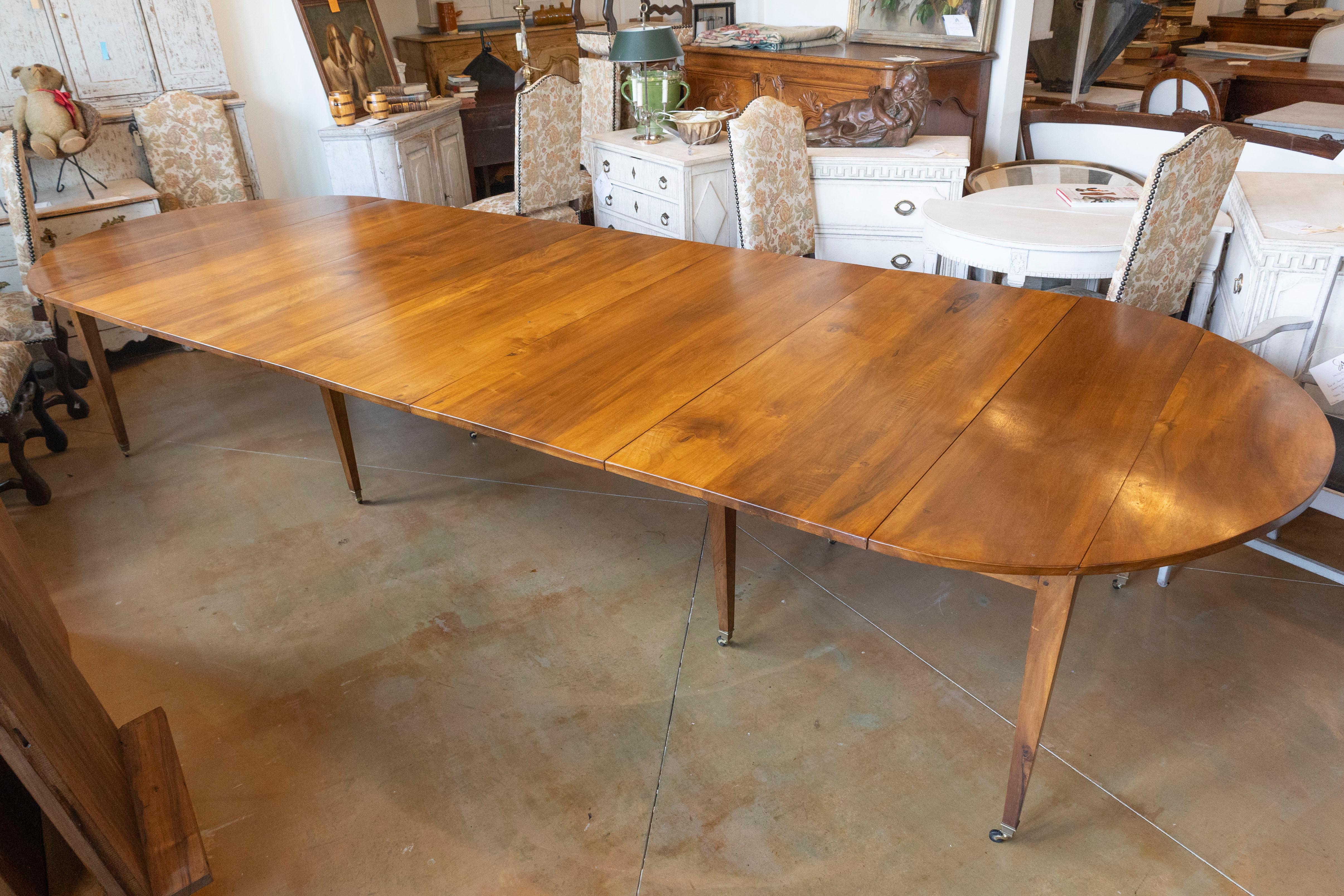 Esta elegante mesa de comedor extensible francesa del siglo XX aporta practicidad y sofisticación francesa atemporal a cualquier comedor. Fabricado con madera de alta calidad, probablemente nogal o caoba, presenta una rica pátina que realza su