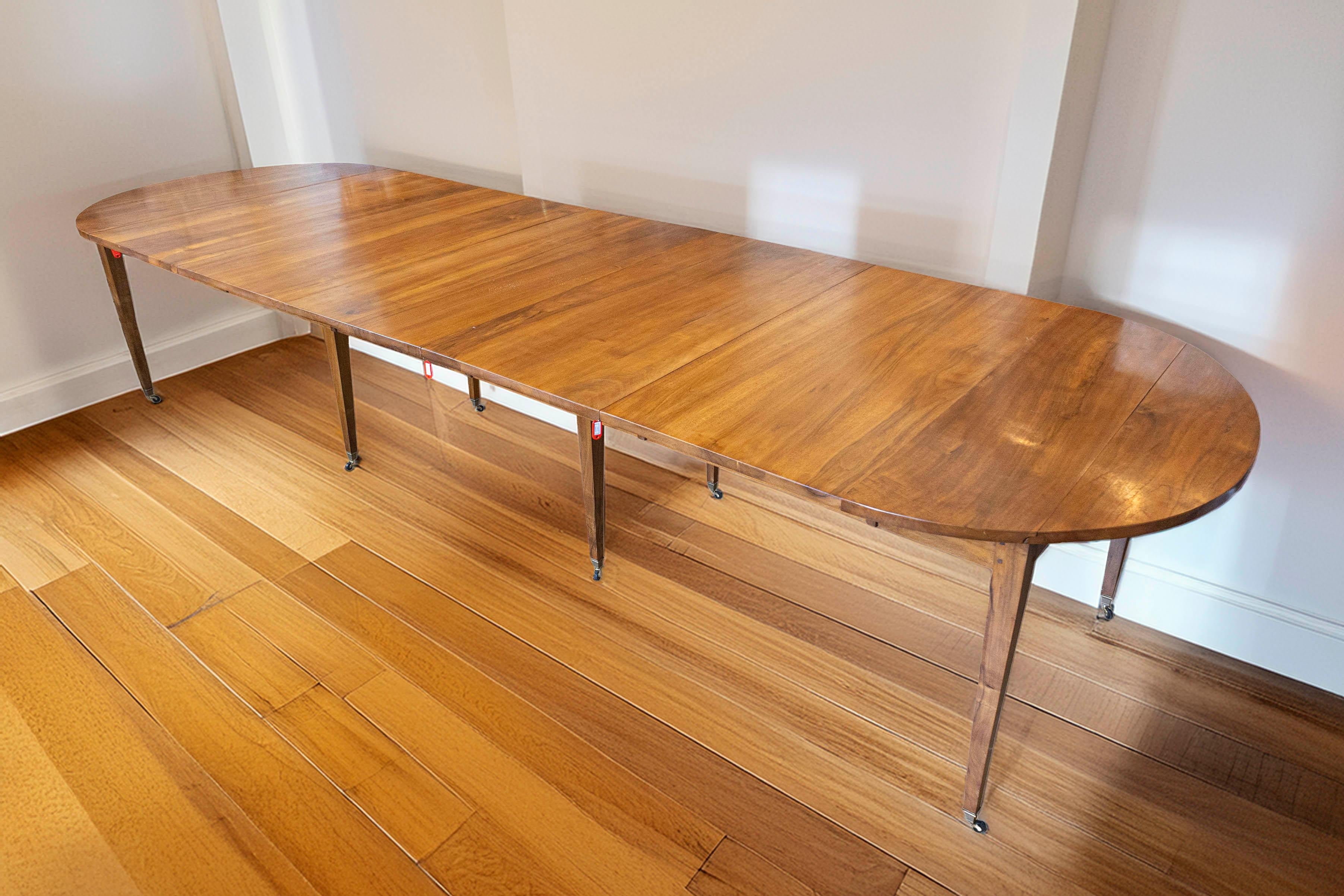 Esta elegante mesa de comedor extensible francesa del siglo XX aporta practicidad y sofisticación francesa atemporal a cualquier comedor. Fabricado con madera de alta calidad, probablemente nogal o caoba, presenta una rica pátina que realza su