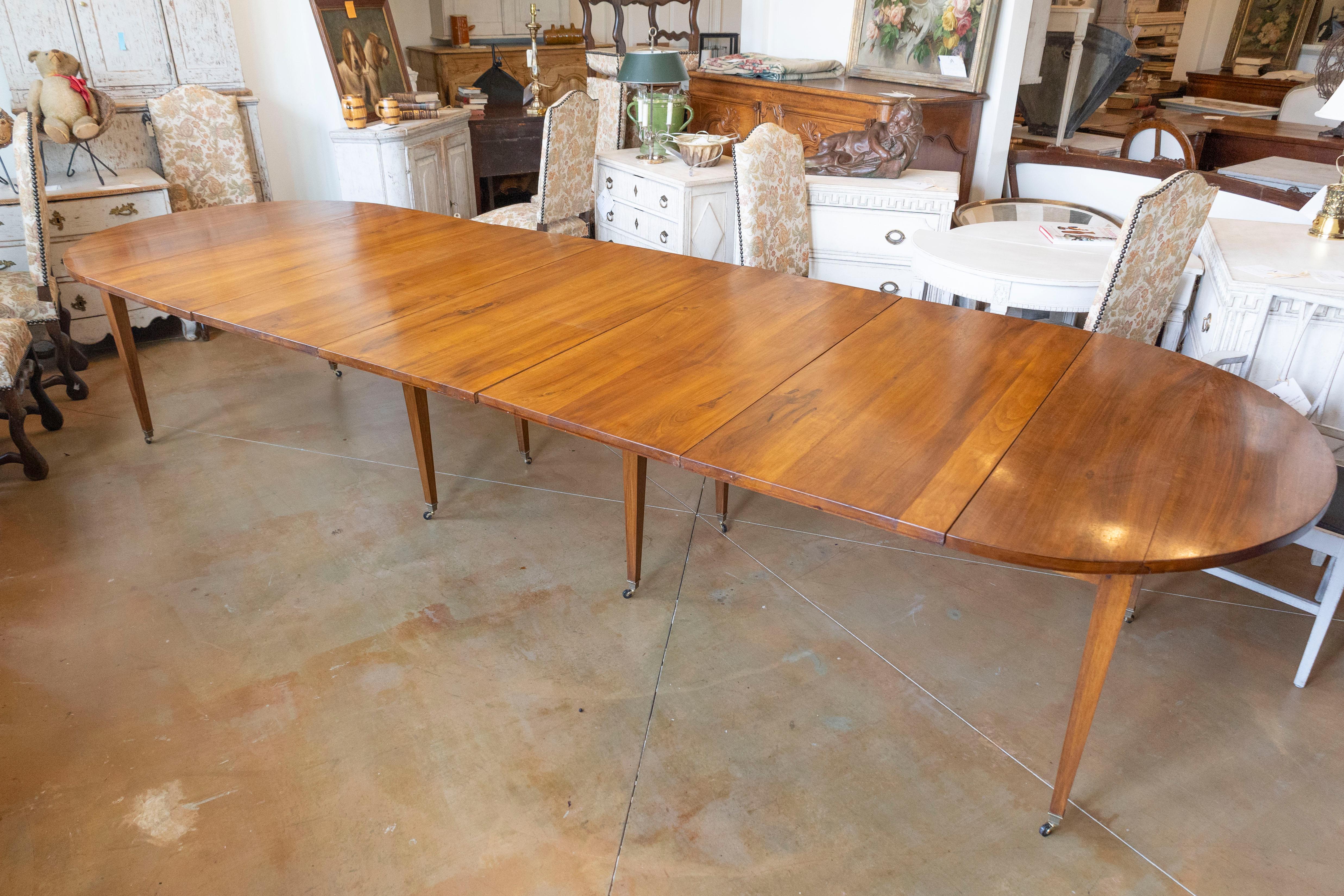 This elegant 20th Century French extension dining table combines functionality with refined design, perfect for both intimate gatherings and large dinner parties. Crafted from fine wood, likely walnut or mahogany, this table showcases a rich, warm
