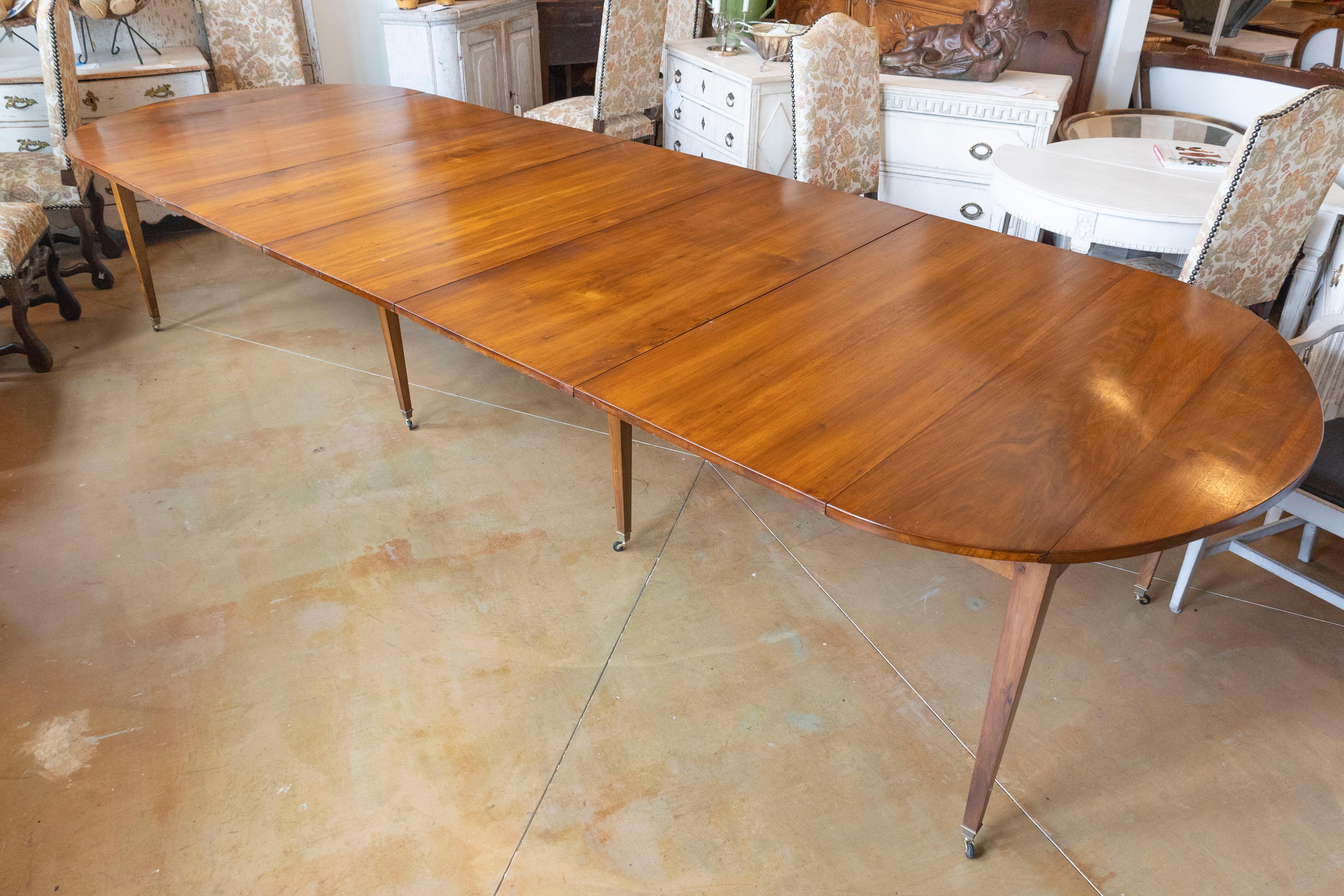 This elegant 20th Century French extension dining table combines functionality with refined design, perfect for both intimate gatherings and large dinner parties. Crafted from fine wood, likely walnut or mahogany, this table showcases a rich, warm