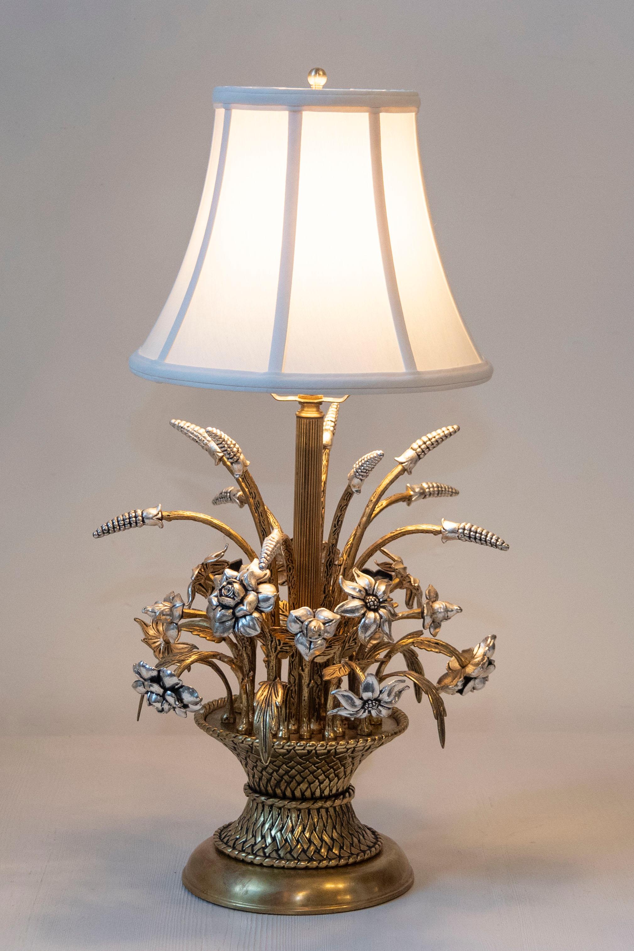 Esta exquisita lámpara de mesa francesa del siglo XX combina elegancia y arte en un diseño floral único. La base de la lámpara, elaborada con gran atención al detalle, presenta una asombrosa disposición de trigo y flores doradas, que recuerda a un