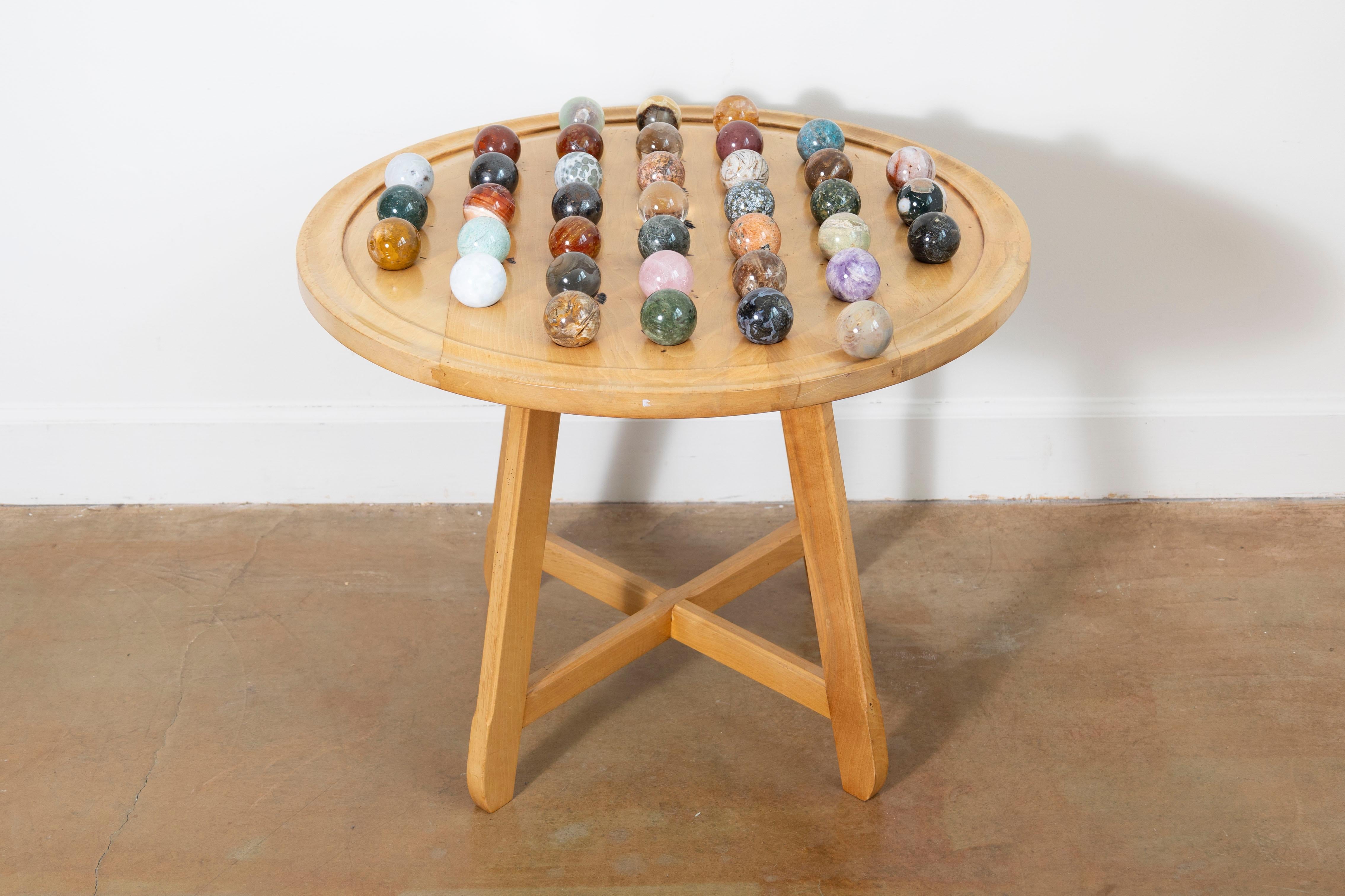 Questo tavolo da gioco francese del XX secolo è un esempio affascinante di artigianato e cultura del tempo libero della metà del secolo. Il tavolo circolare, realizzato in legno naturale, presenta una finitura liscia e chiara che mette in risalto le