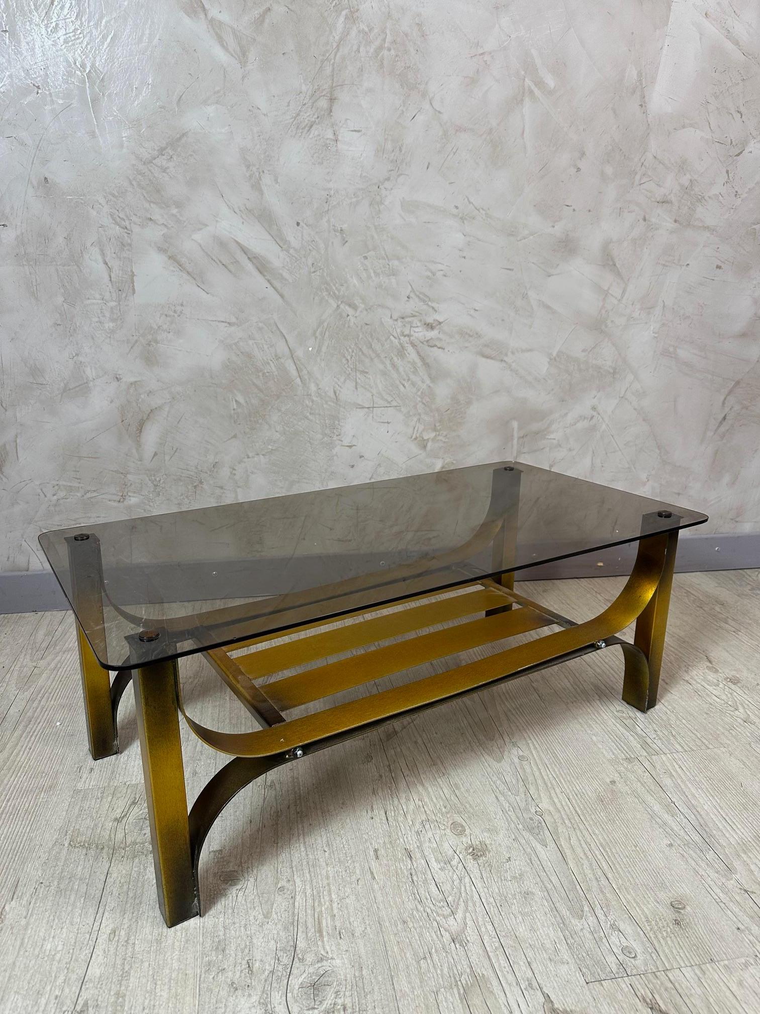 Bellissimo tavolino vintage con struttura in metallo dorato e piano in vetro fumé. Il suo design leggero include un ripiano inferiore ideale per riporre riviste o oggetti decorativi.

Un pezzo versatile che si adatta facilmente agli interni moderni