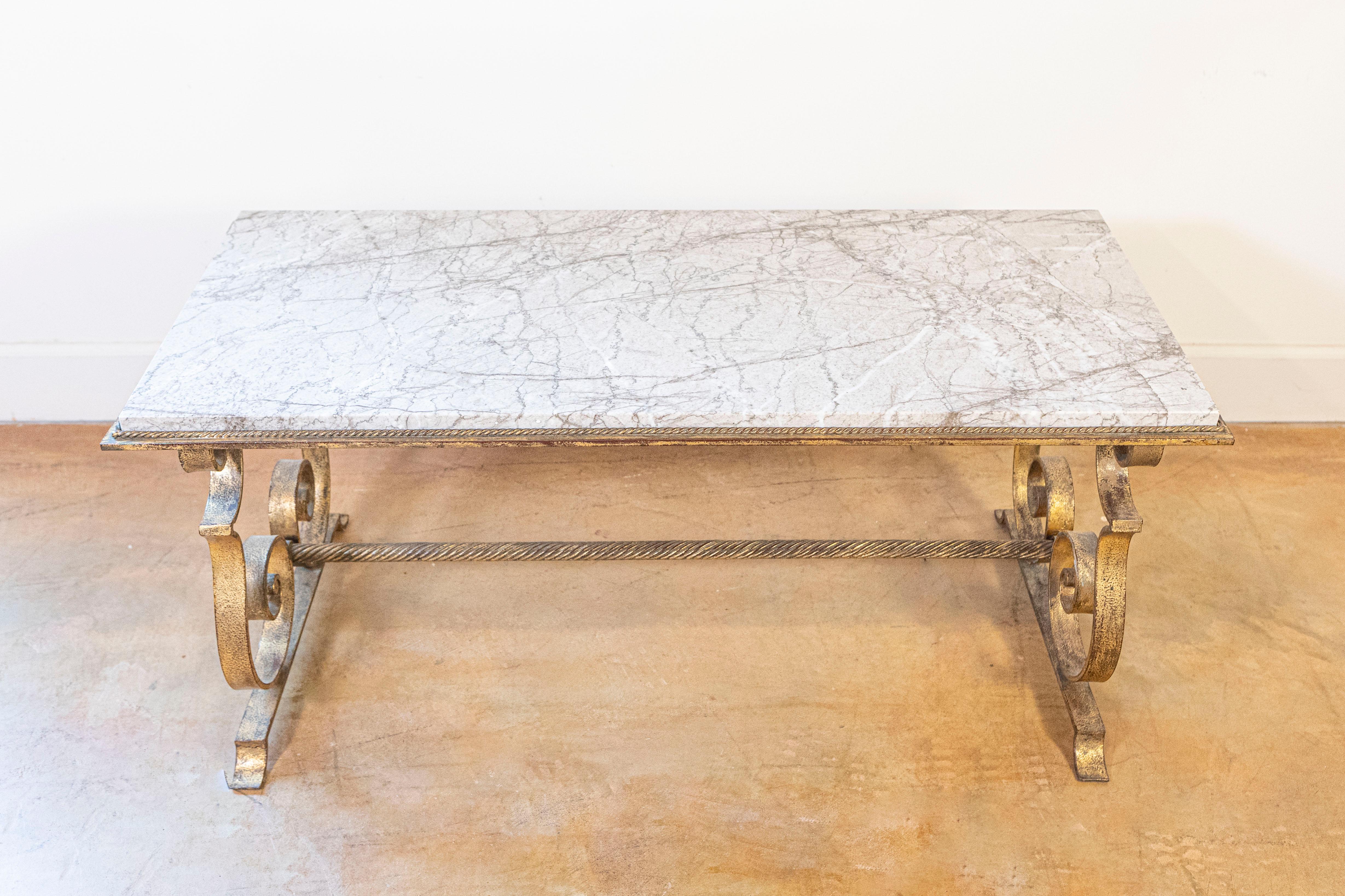 Cette élégante table basse française du 20e siècle incarne le style sophistiqué et l'artisanat du design français du milieu du siècle. La table présente un superbe plateau rectangulaire en marbre avec un motif classique de veinage blanc et gris, qui