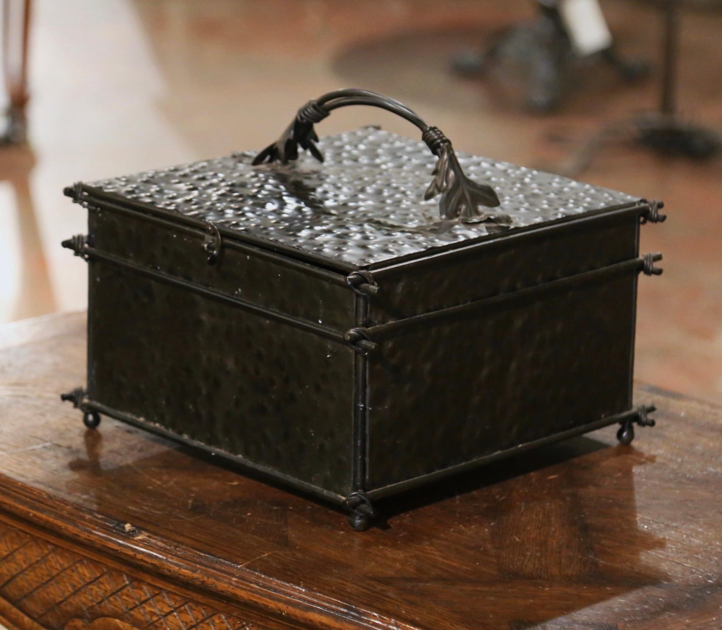 This beautifully executed square box crafted circa 1990 is embellished with a handle made into a twisted branch form with a leaf accented on either side, a latch on the front firmly secures the top. The small container features hammered iron with