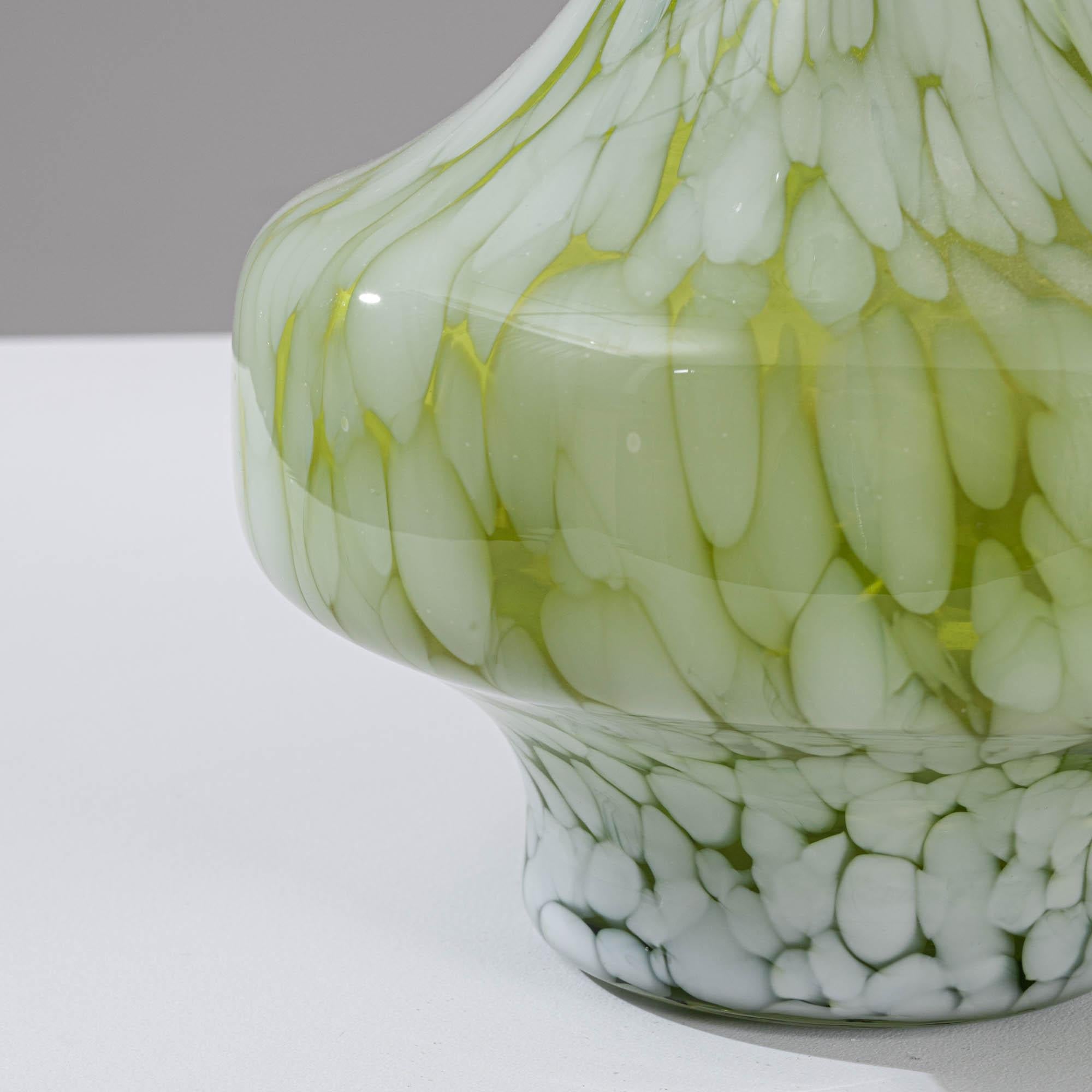 Elevate your décor with this exquisite 20th-century French Green Glass Vase. The lush green hue exudes a timeless elegance, enhanced by delicate white confetti melts gracefully dispersed across the surface. This striking vase is designed with a