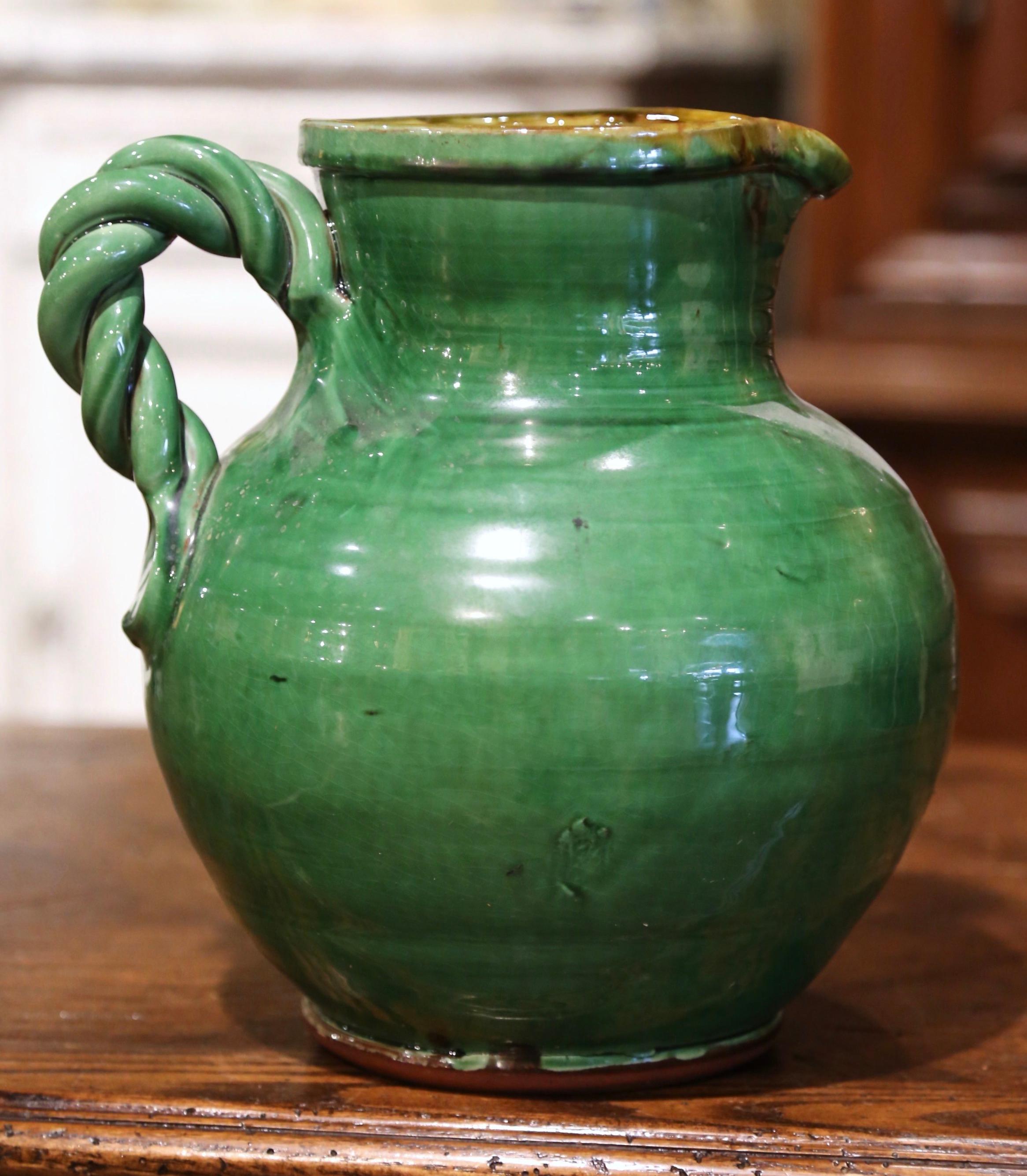 Decorate a kitchen with this elegant vintage water or wine pitcher. Hand crafted in Southern France circa 1980 and made of earthenware, the pottery piece is round in shape and dressed with a twisted handle; it has a glazed finish in the traditional