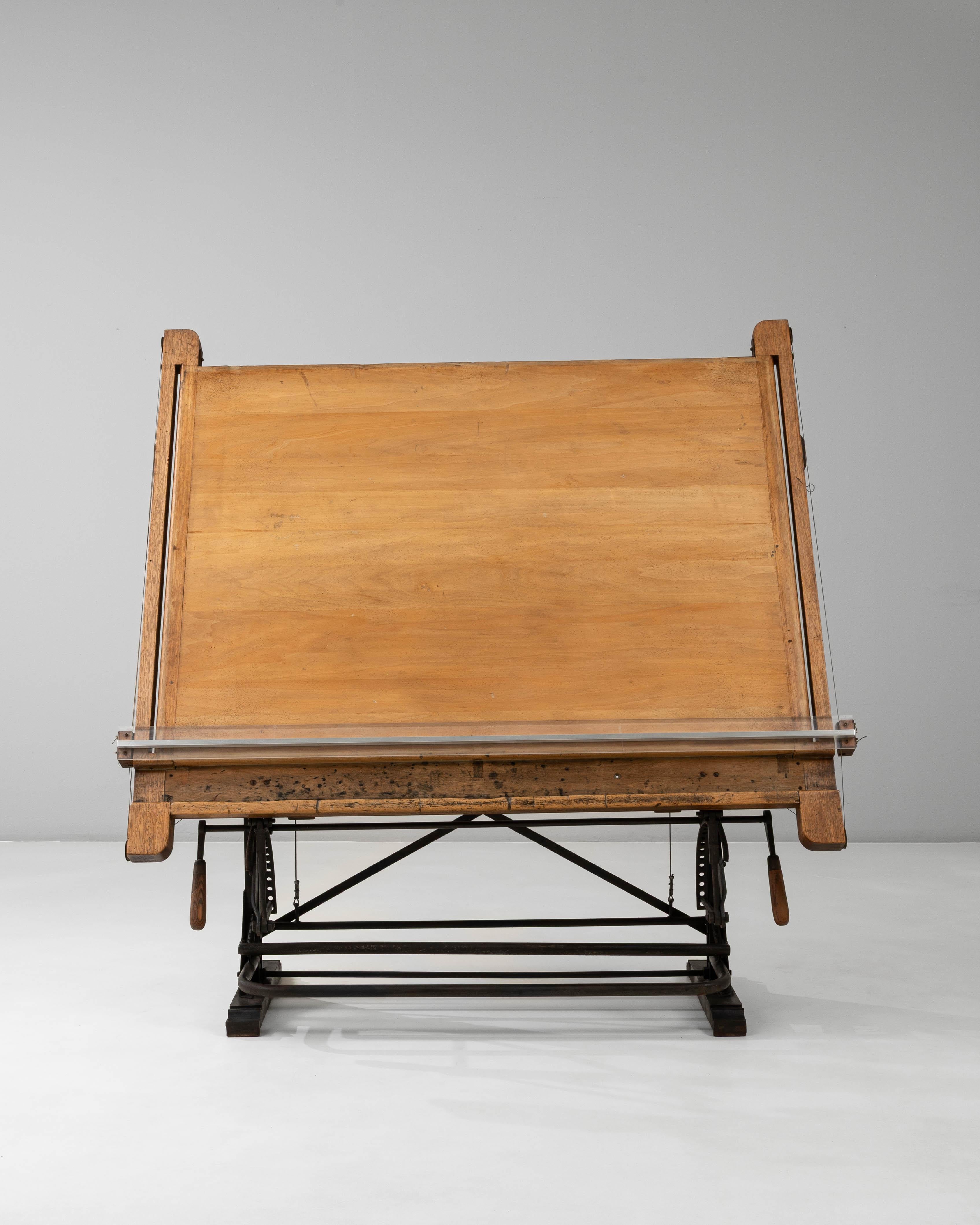 This 20th-century French industrial drafting table features an impressive combination of solid wood and cast iron, showcasing exceptional craftsmanship and mechanical precision. The broad wooden top, beautifully aged with a natural patina, rests