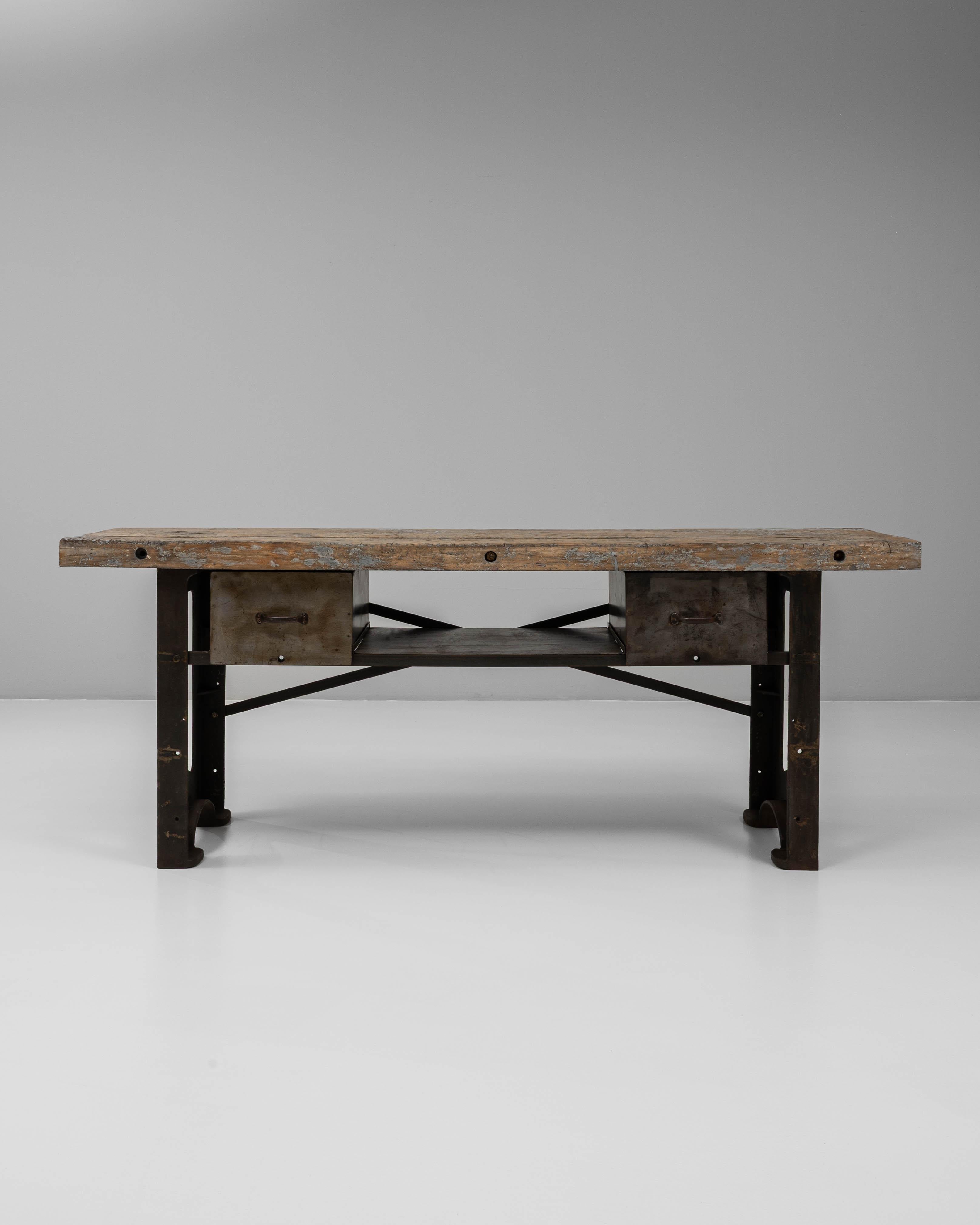 Cette table de travail en fonte industrielle française du 20e siècle avec plateau en bois est un exemple puissant de l'artisanat des premières usines, combinant l'utilité brute avec une présence sculpturale. La lourde base en fonte, marquée par des