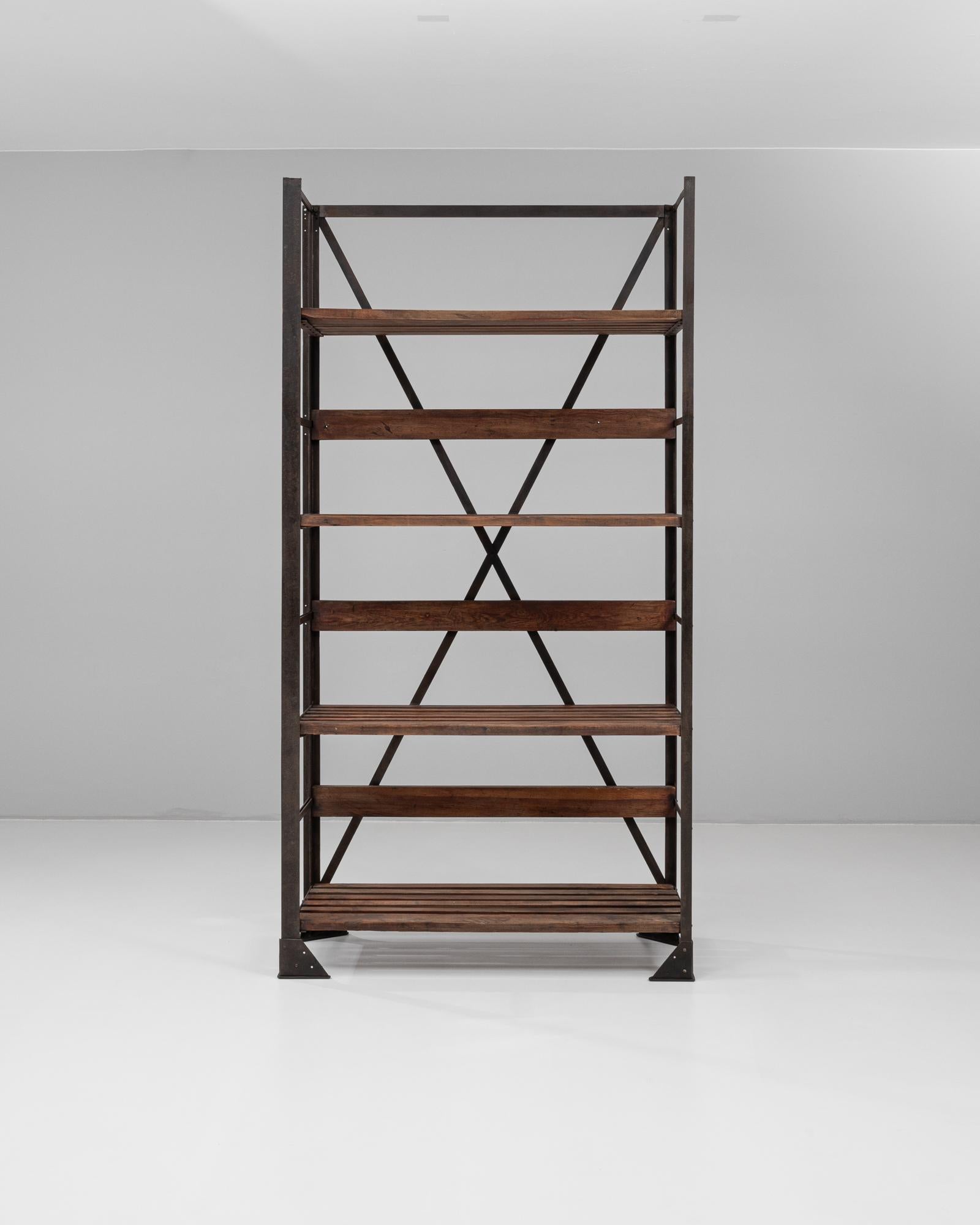 This 20th century French industrial bookshelf combines utilitarian function with robust materials, offering a striking presence through its iron frame and wooden shelving. The structure features six spacious shelves, some solid and others slatted,