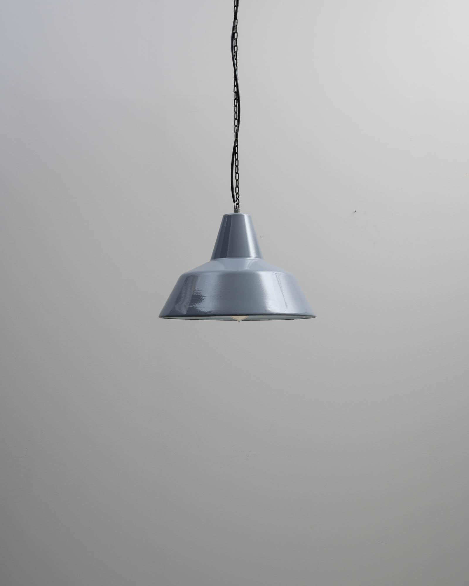 An industrial style metal lighting fixture created in 20th century France. Neatly composed and satisfyingly minimal, this mid-century style lighting fixture effortlessly exudes a chic sense of style. The simple metal shade is coated with a luscious
