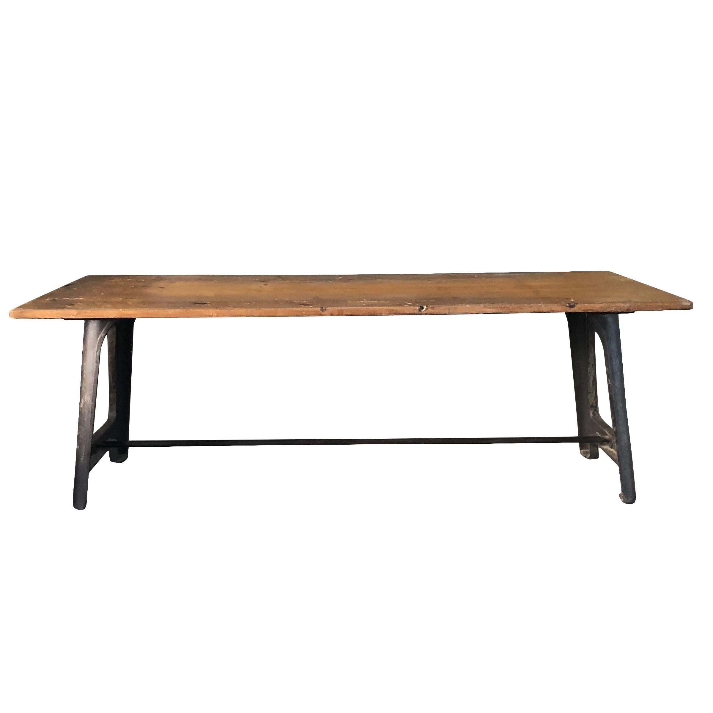 An antique rustic French industrial table made of a pinewood table top and a cast iron base with metal tresses lateral bolts. Wear consistent with age and use, circa 1910, France.