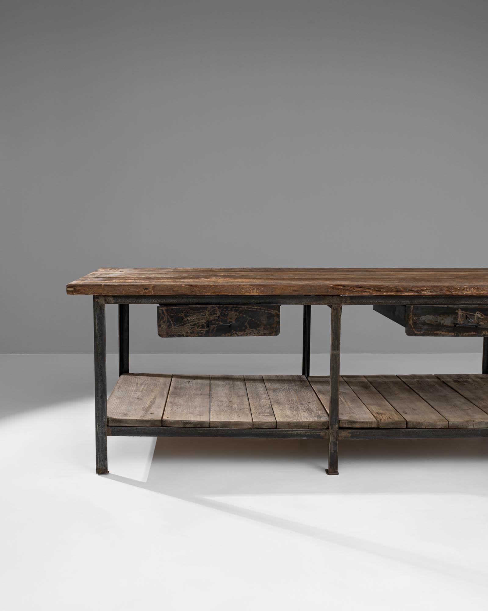 This 20th Century French Industrial Table is a magnificent find for lovers of unique and functional vintage furniture. It features a robust, rectangular top crafted from weathered wood that adds a deep, rich character to the piece. Supported by a