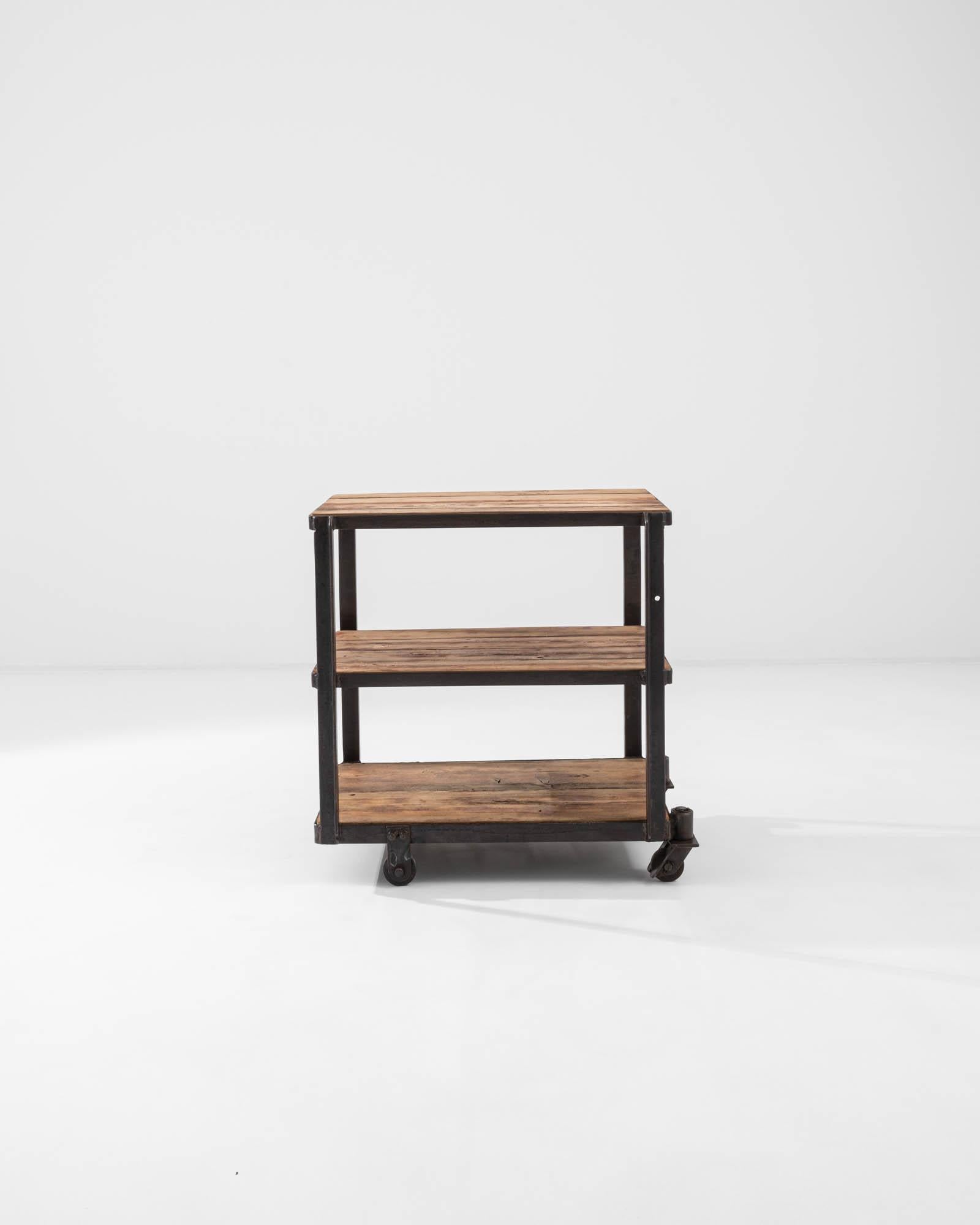 Robust and versatile, this vintage Industrial storage unit combines a pragmatic design with a warm patina. Made in France in the 20th century, a trio of spacious wooden shelves are held within a right-angled iron frame. The metal has weathered to a