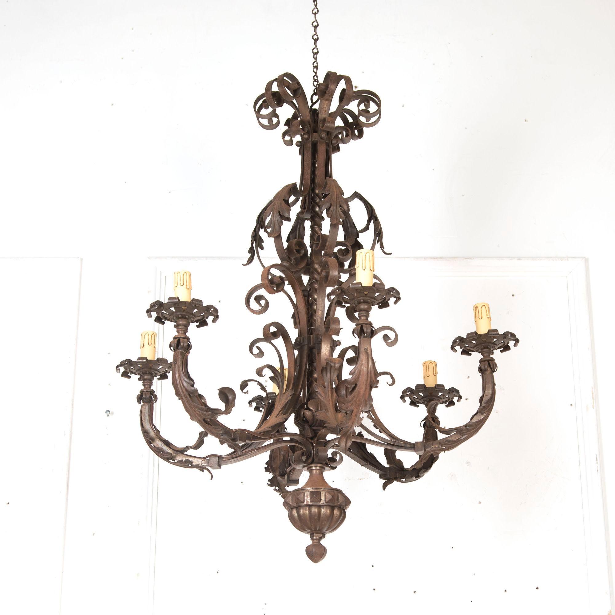 French six-armed iron chandelier, circa 1950.The arms and central shaft feature scrolling acanthus leaves in alternating directions. This chandelier has a great composition with an imposing presence that is minimised by the pretty scroll detailing