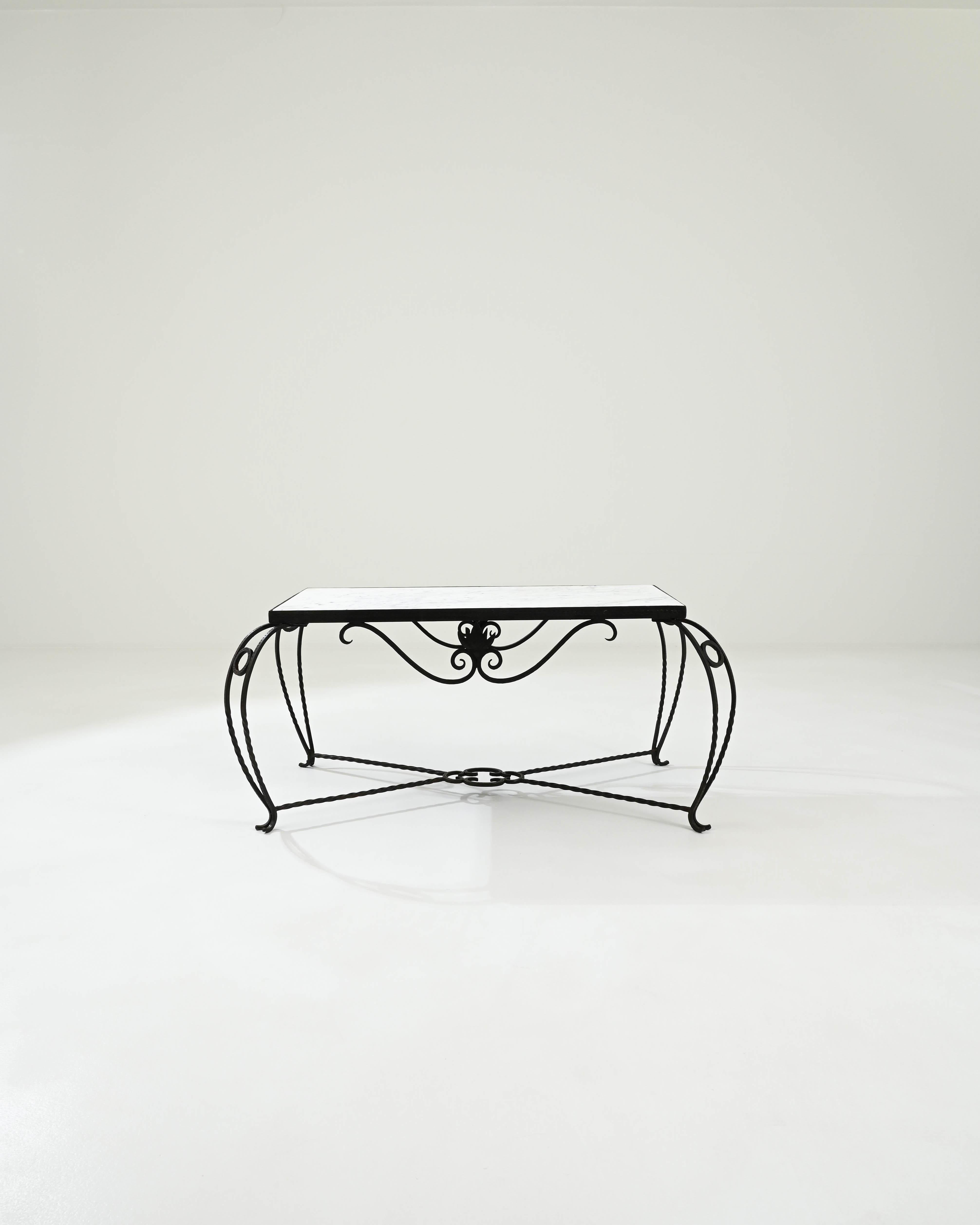 This exquisite coffee table was made in 20th-century France.The elaborate detailing of the wrought iron base interplays with the luxurious white marble tabletop, which features ethereal patterns reminiscent of clouds in the sky. Combined with the