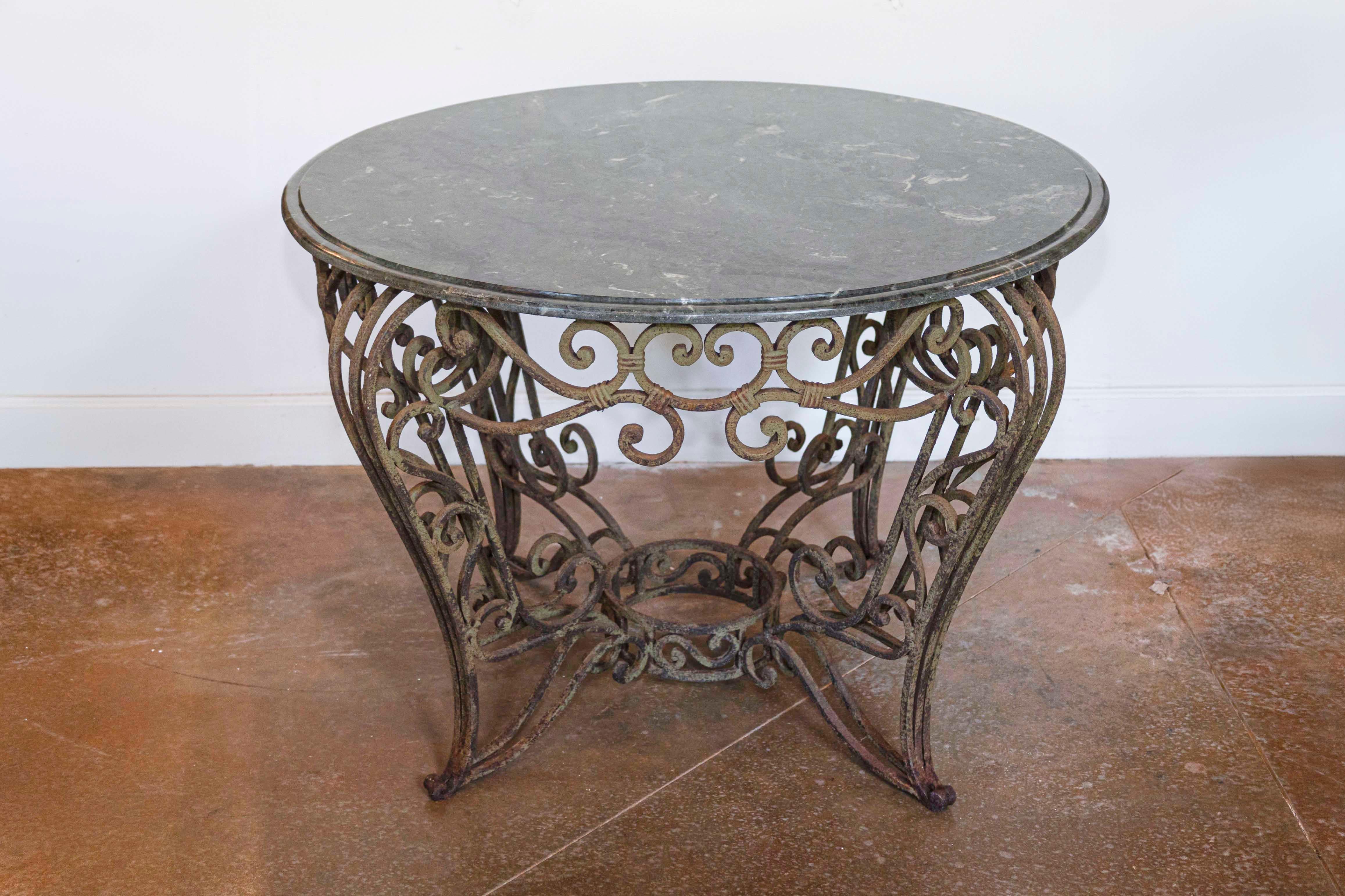 Cette exquise table centrale ronde française est une combinaison magistrale de fer forgé et de marbre Verde, incarnant l'élégance fluide du design Art nouveau du début du 20e siècle. La base en fer présente des volutes complexes forgées à la main,