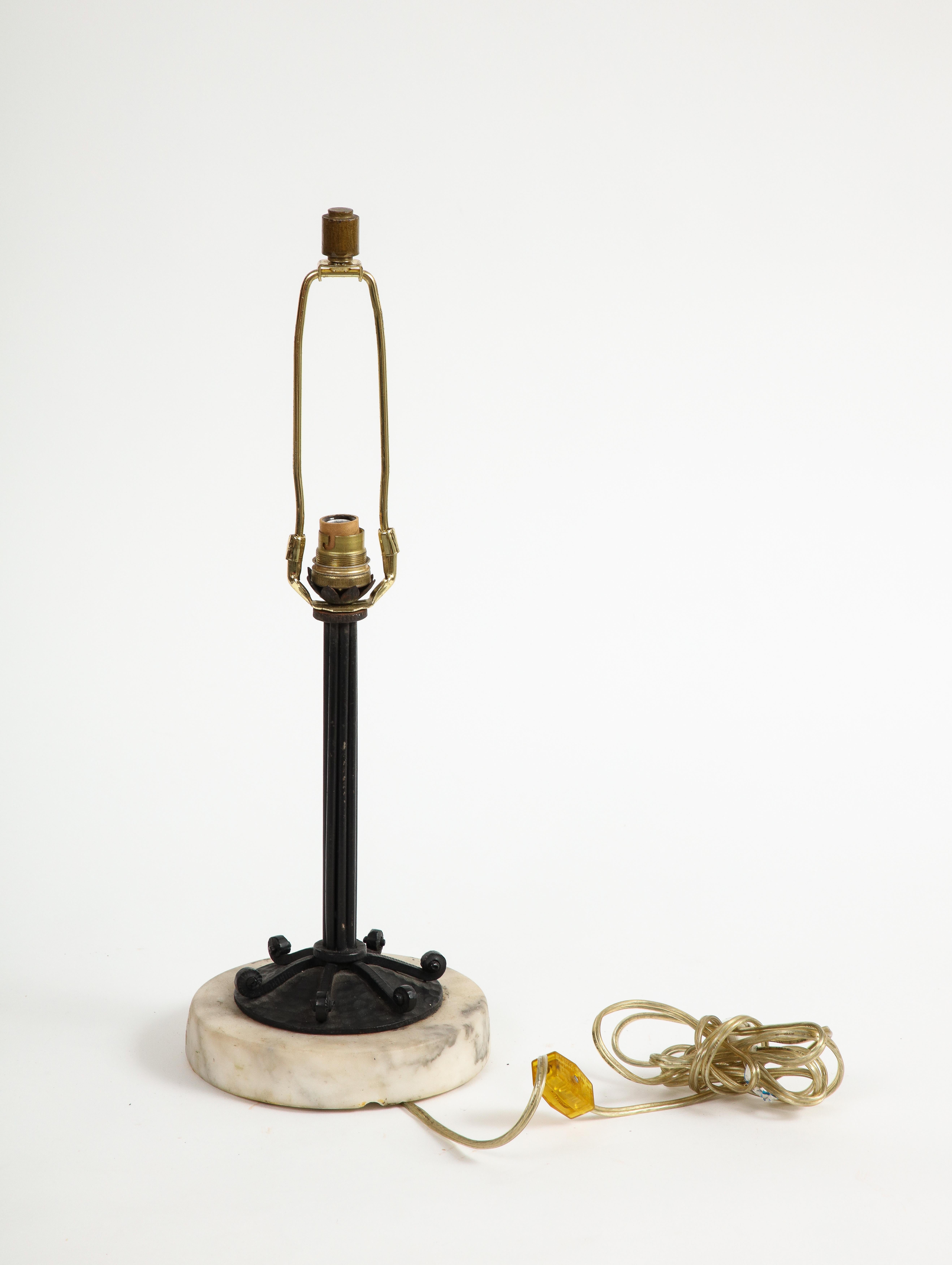 20th Century French wrought iron table lamp on marble base, featuring leaf decoration at the base of the socket and coiled wrought iron lines on the lamp base.