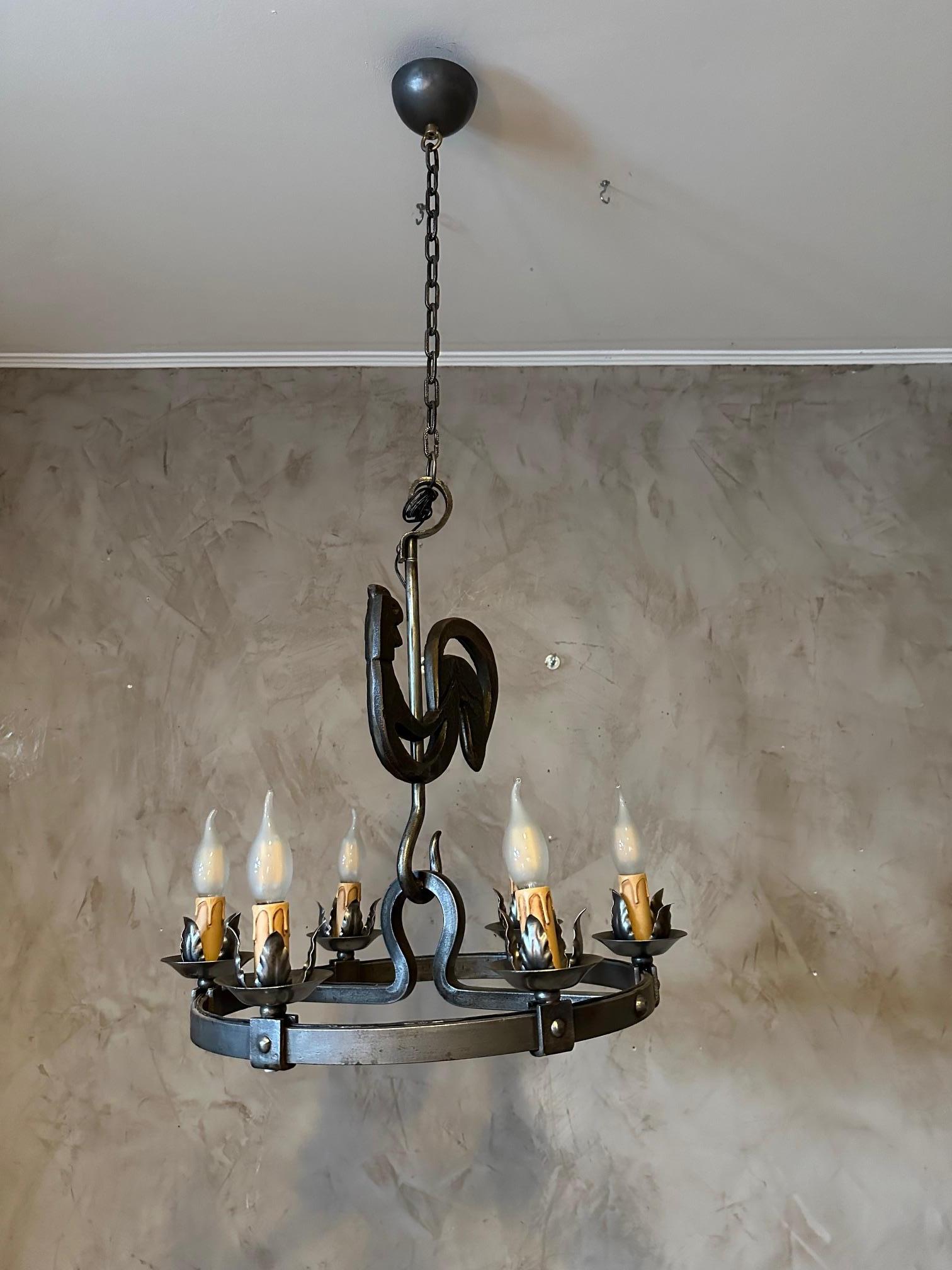 Wrought iron chandelier dating from the 1950s made by Jean Touret for the Marolles workshops in France. 
Rooster represented on the top of the chandelier, very beautiful iron work.
Six bulbs, fully electricity.

History of Jean Touret:
A young