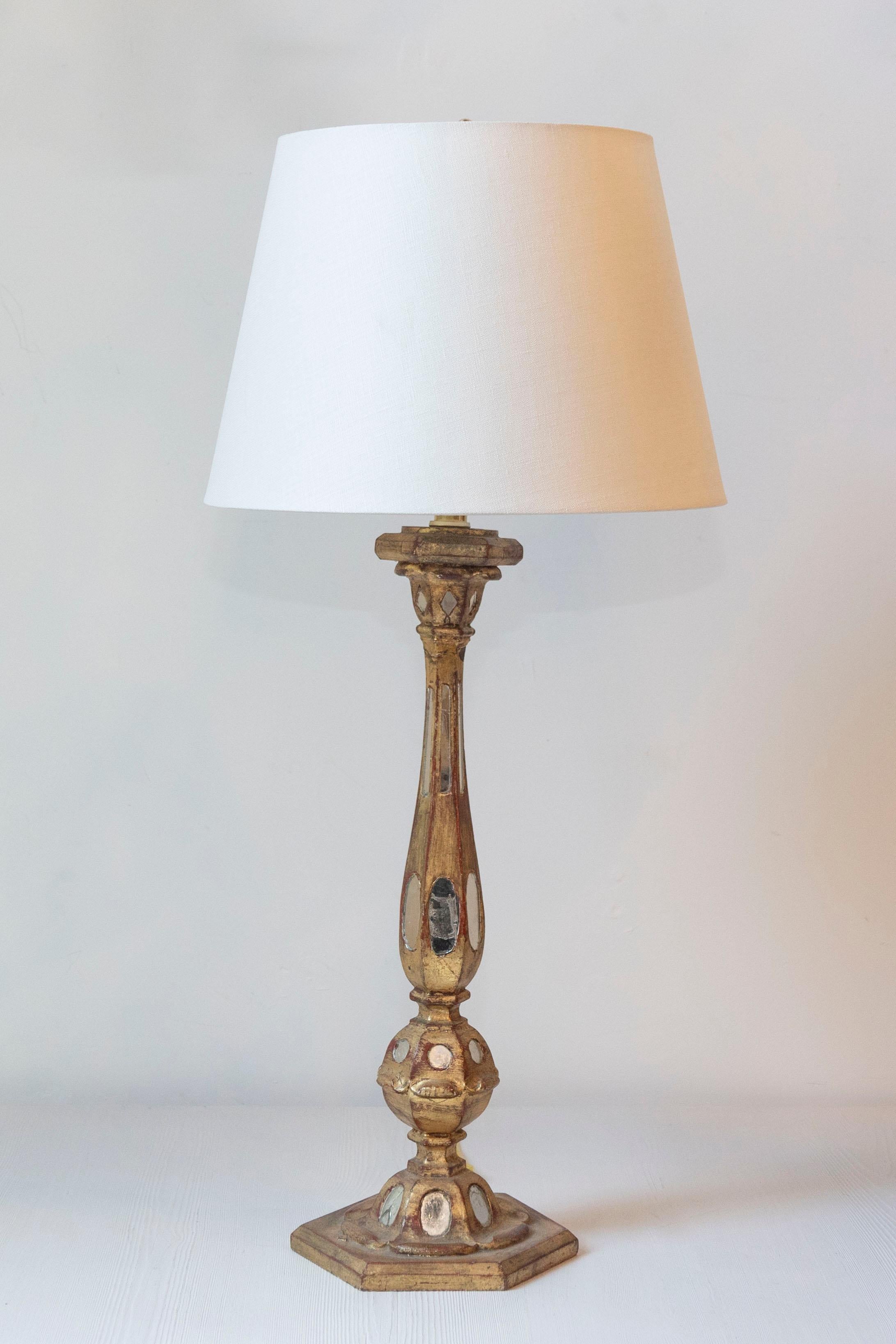 This 20th-century French lamp exudes timeless elegance and artisanal craftsmanship, making it a striking addition to any interior. Crafted from gilded wood, it features a gracefully elongated baluster form adorned with intricate details, including