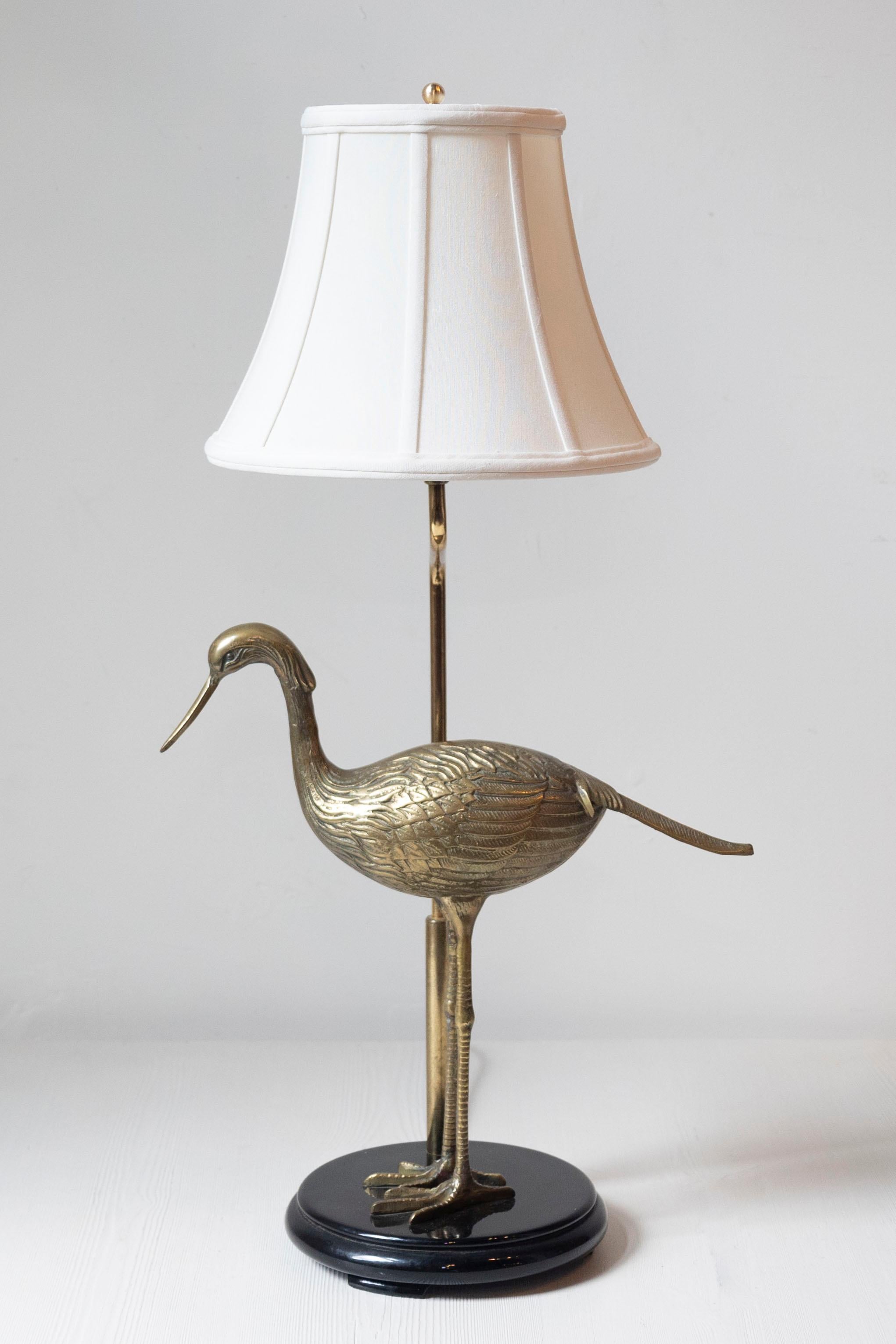 Cette lampe française du XXe siècle est un charmant exemple d'art fonctionnel, mêlant éléments naturalistes et décoratifs. La base présente un oiseau en laiton magnifiquement moulé, probablement une grue ou un héron, qui se tient gracieusement sur
