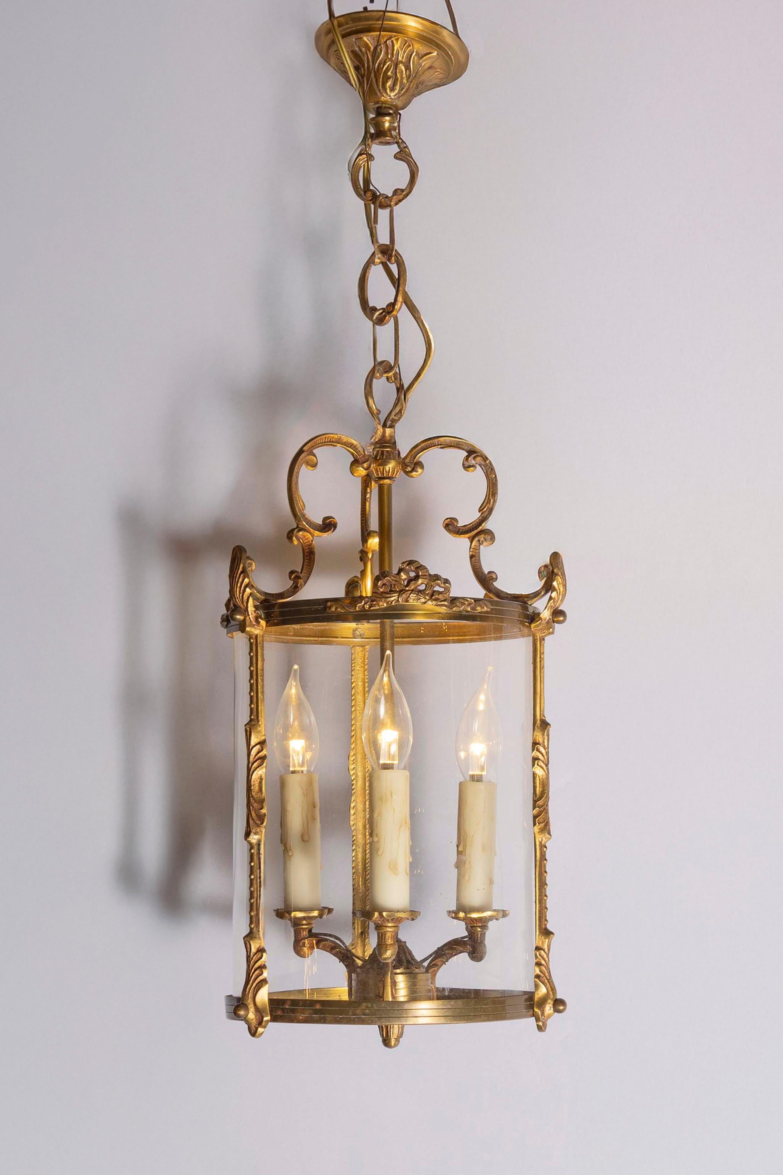 Este exquisito farol francés del siglo XX muestra una elegancia atemporal y una refinada artesanía. Su marco de metal dorado, adornado con volutas ornamentales y detalles intrincados, encarna la sofisticación del diseño neoclásico. El farol cuenta