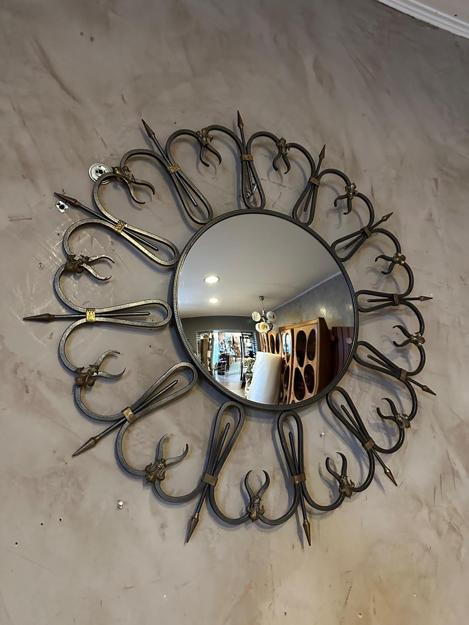 Très beau miroir des années 60 en fer forgé et miroir de sorcière incurvé. Décoration de fleurs de lys. Crochet au dos pour accrocher le miroir au mur. Magnifique travail de ferronnerie. Miroir très élégant et en bon état.