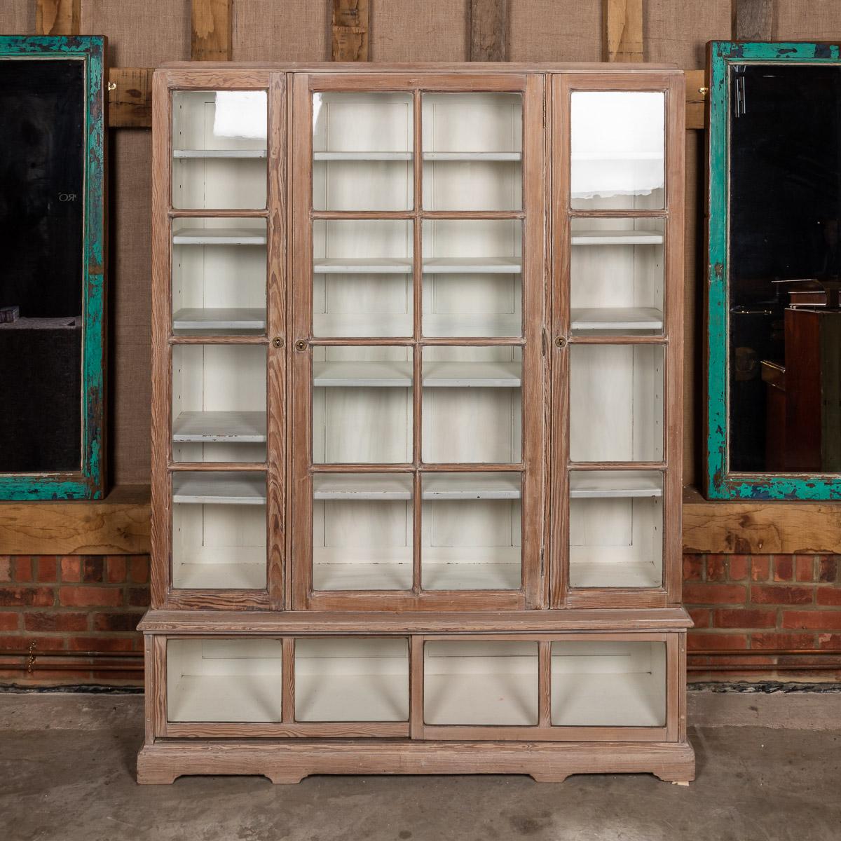 Antique early-20th century French glass-fronted limed display cabinet with four storage drawers to the base.

Measures: Height: 203cm
Width: 158cm
Depth: 38cm.