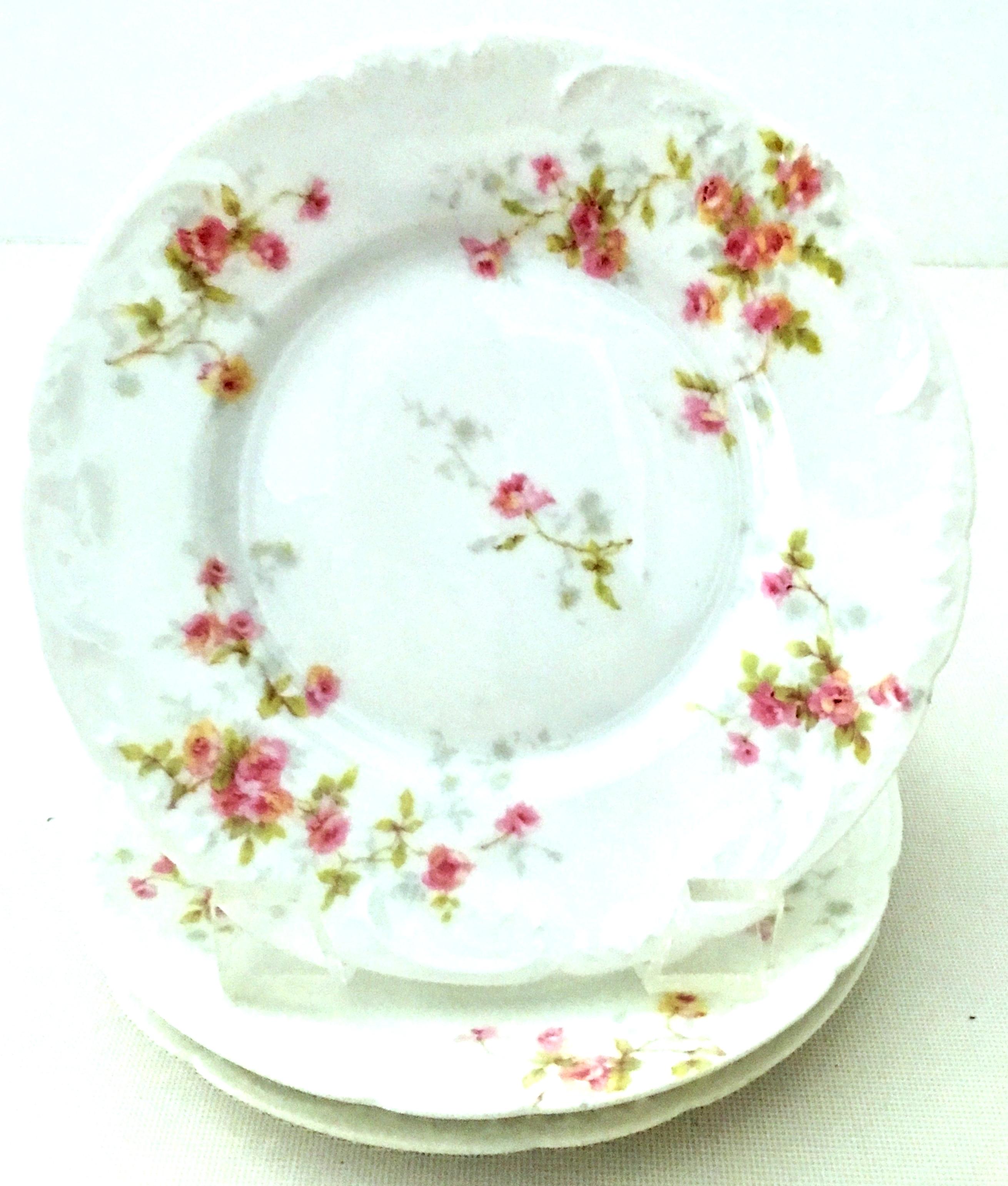 20th century French Limoges Porcelain dinnerware by Theodore Haviland set of nine pieces. Set features a bright white ground with scalloped shape detail, hand painted in a bright pink and green flowing rose pattern. Set includes, 5 luncheon plates,