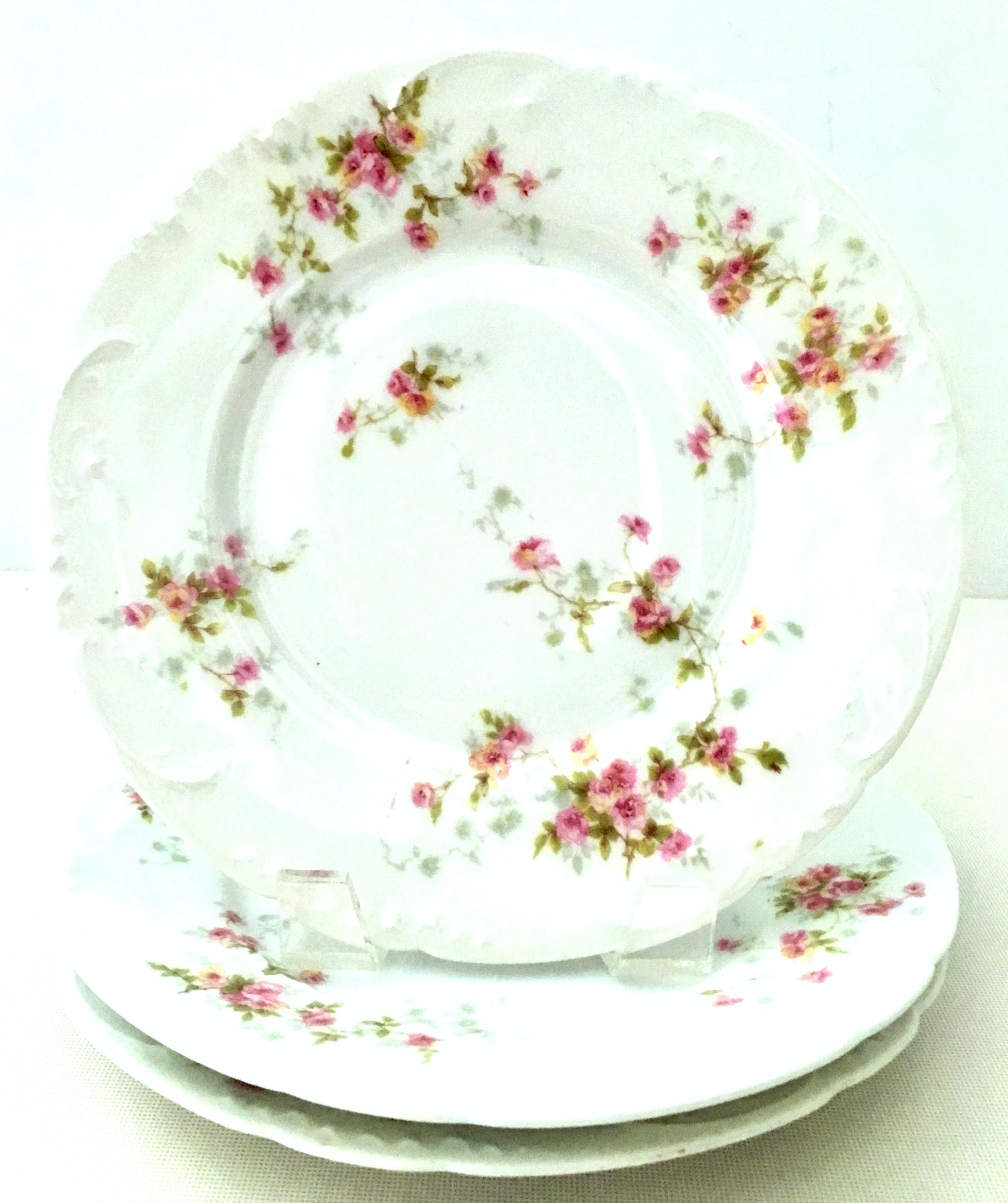 20th century French Limoges dinnerware by Theodore Haviland set of nine pieces. Set features a bright white ground with scalloped shape detail, hand painted in a bright pink and green flowing rose pattern. This nine piece set includes, three dinner