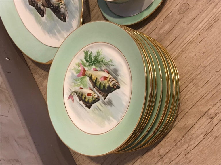 Beautiful 20th century French Limoges Porcelain hand painted fish serveware from the 1950s. 
White porcelain with apple green band, gold edging on the outline, all hand painted
Fish decoration in the center of the plate and on the dish, 6