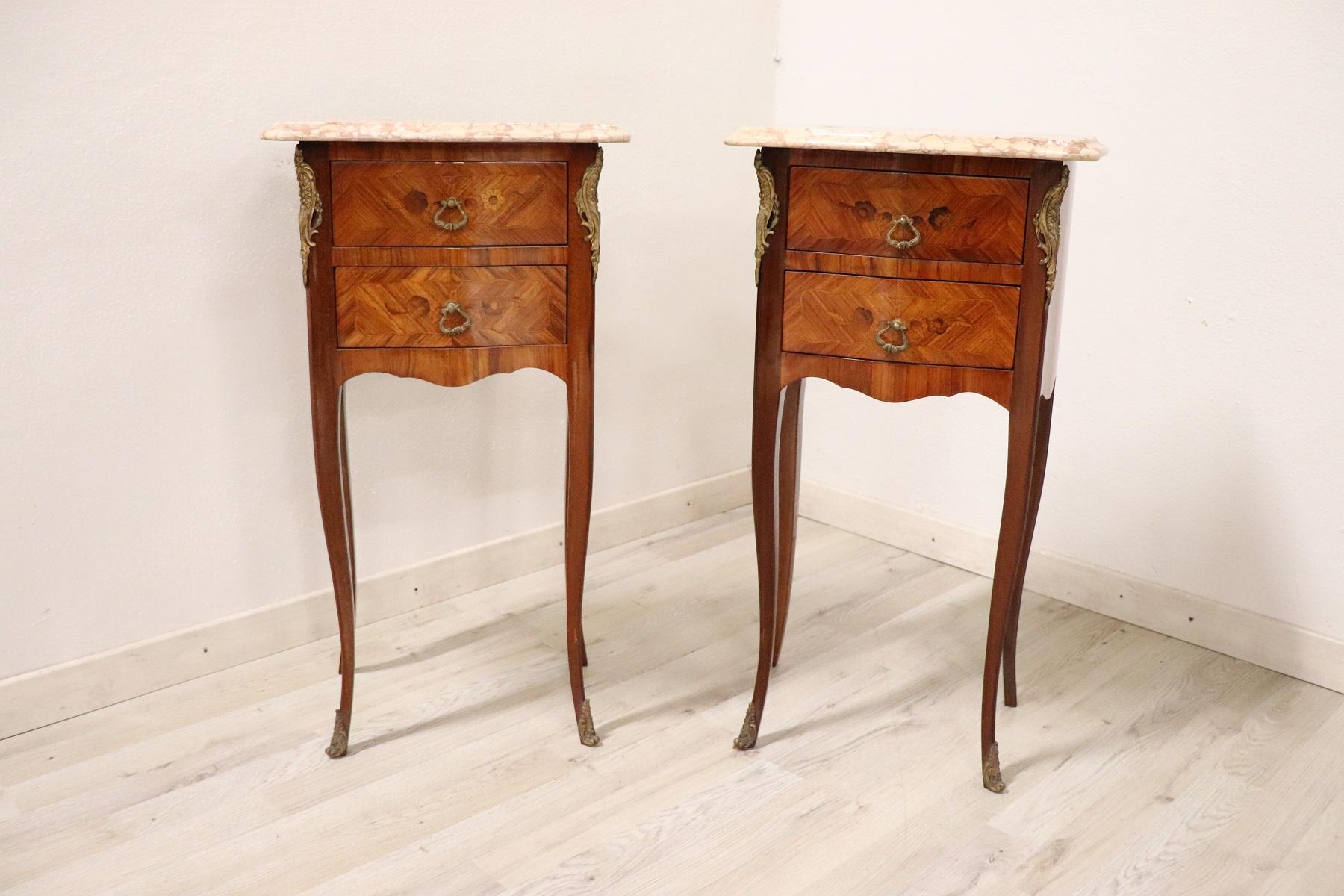 Louis XV style furniture richly adorned with gilded and chiselled bronze. The wood has a delicate floral taste inlay. The top is in precious pink marble. A pair of really elegant bedside tables, ideal in the bedroom but also used in other rooms of