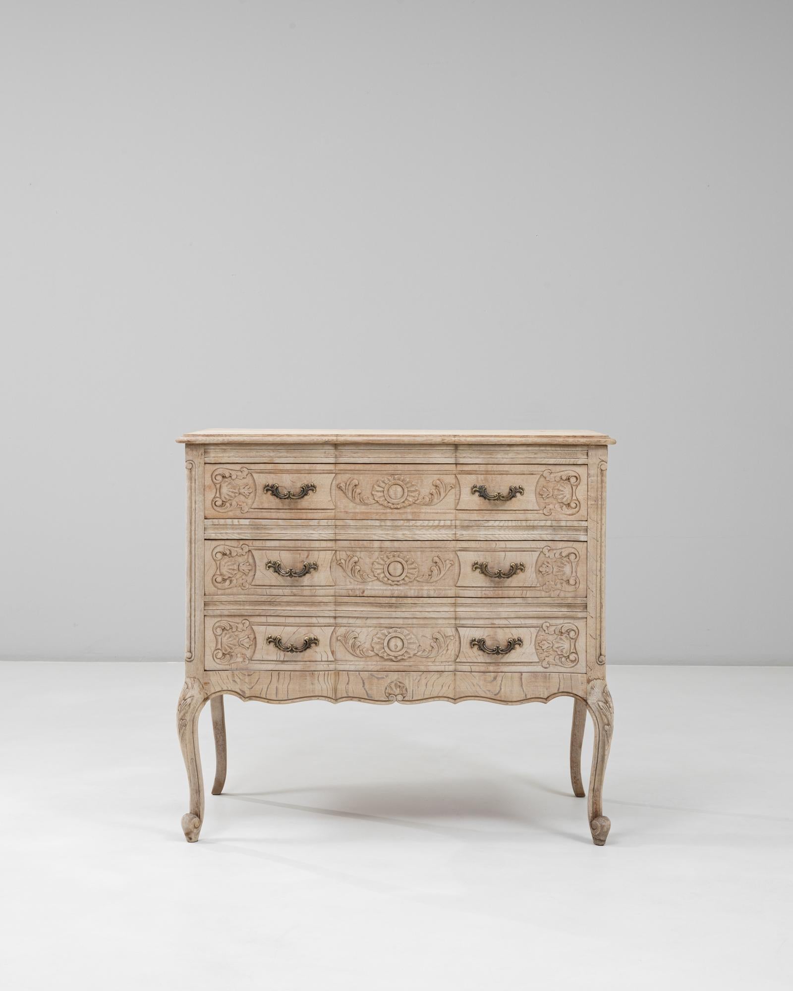 Questa cassettiera in quercia francese del XX secolo in stile Luigi XV presenta proporzioni eleganti e dettagli splendidamente intagliati che definiscono l'estetica raffinata del periodo. Il frontale a serpentina, il grembiule smerlato e le gambe