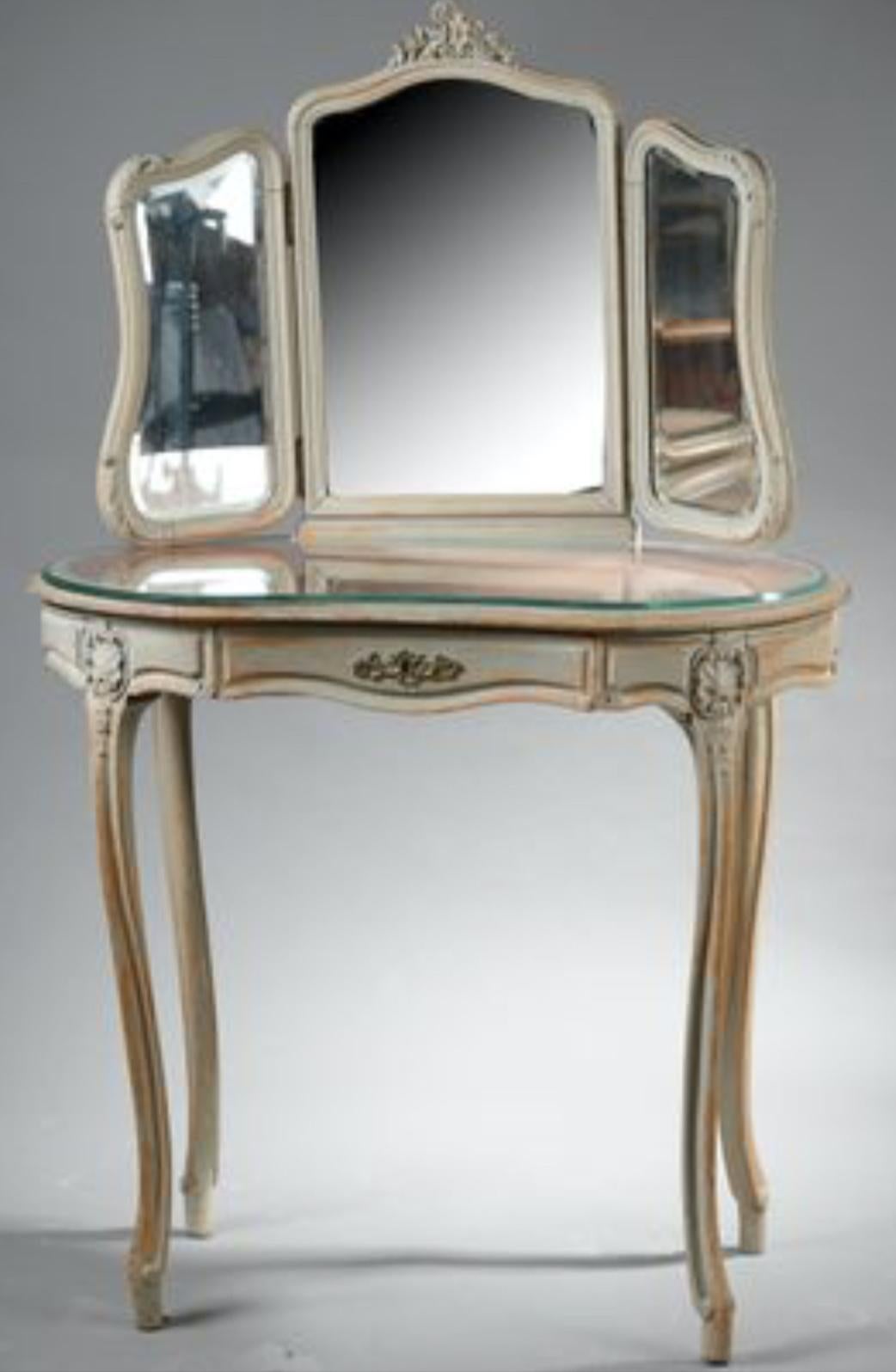 French vanity table in kidney shape made of solid wood hand painted in light green and decorated with floral accents. The table is raised on four long curved legs and has a front drawer and triple mirror.
France, Louis XV style, circa 1920
Very