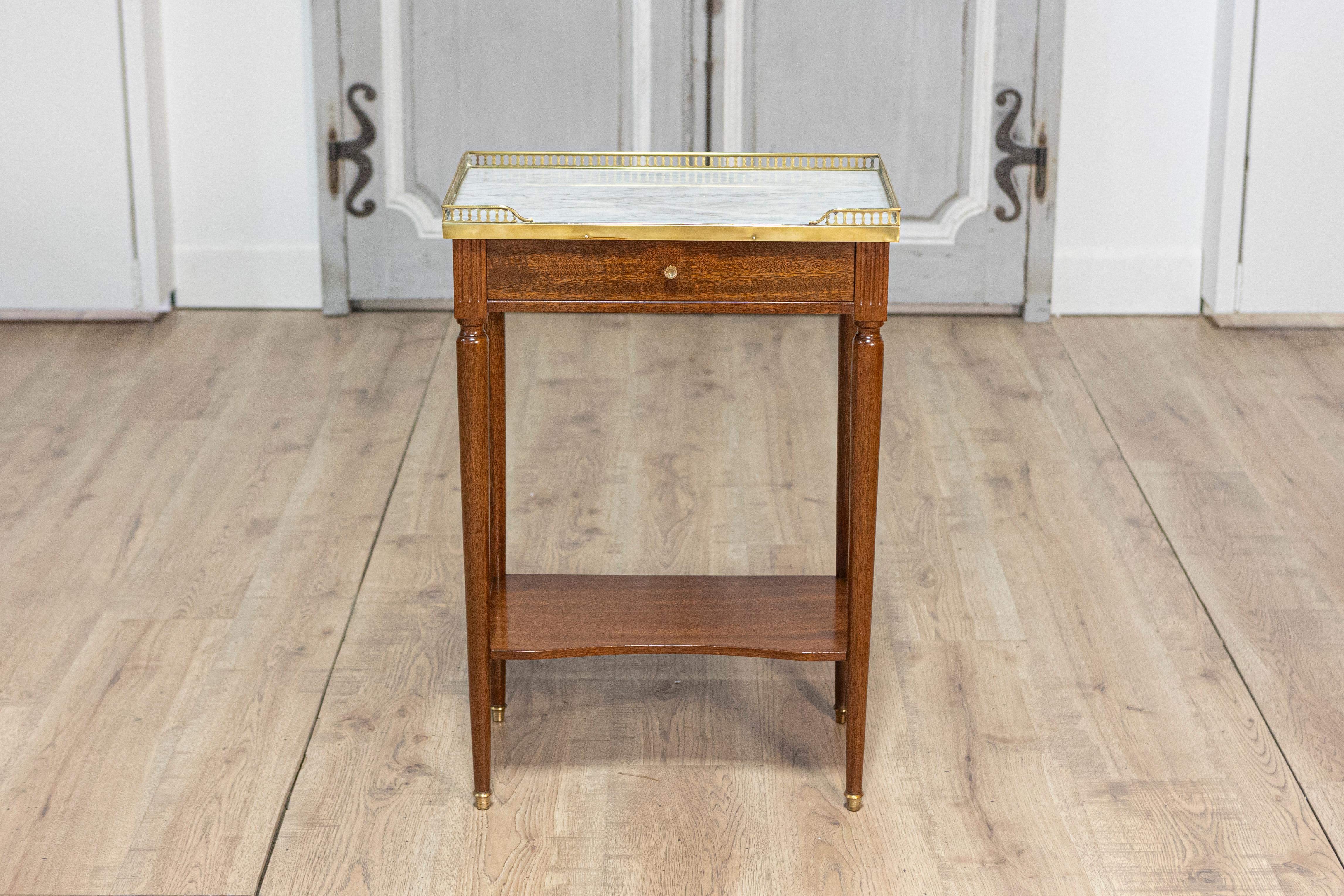 Table d'appoint française de style Louis XVI du XXe siècle, en acajou, aux proportions élégantes et au design intemporel. La table s'ouvre par un seul tiroir en façade, équipé d'un bouton en laiton pour faciliter son utilisation, alliant