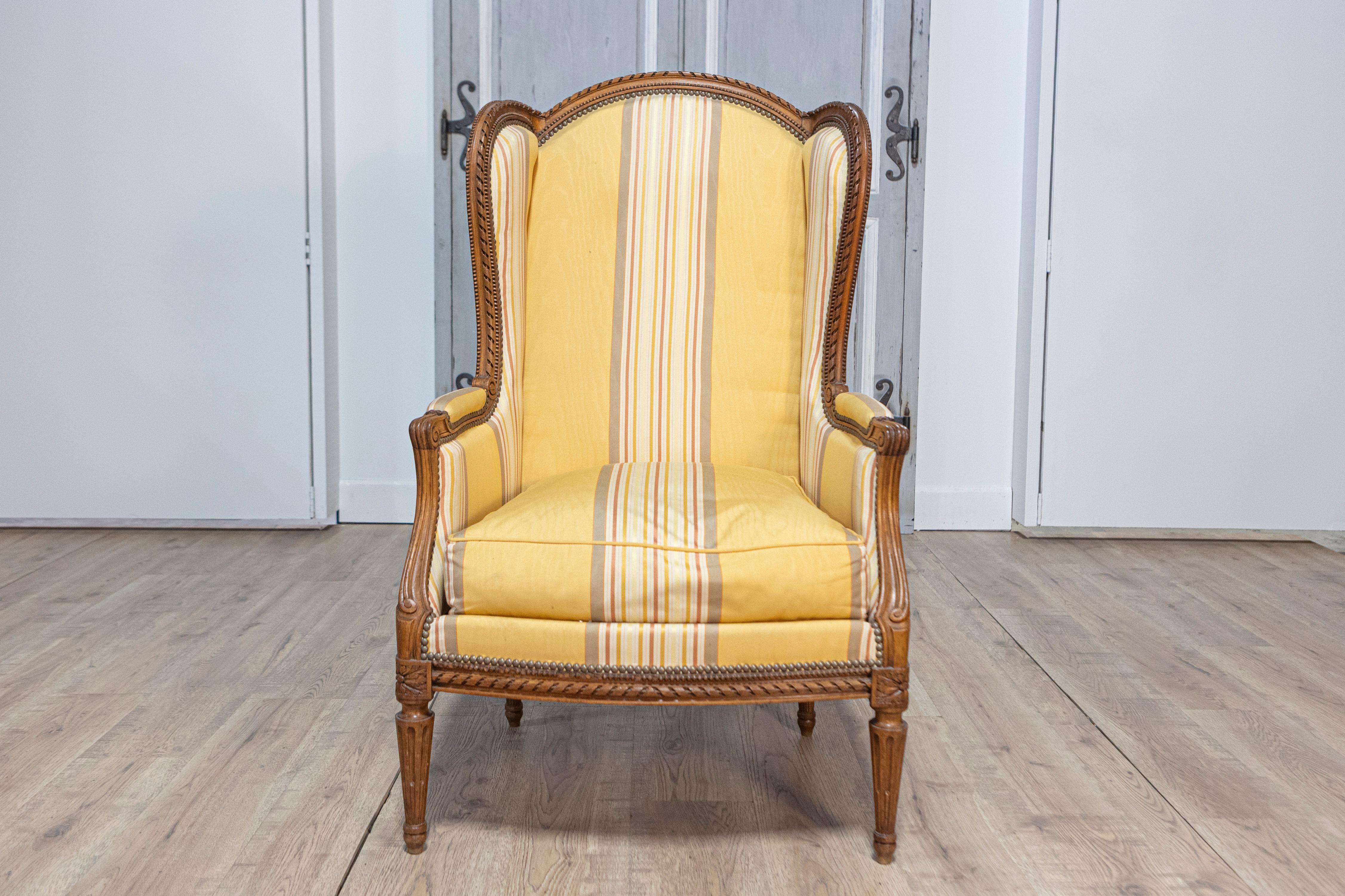 This elegant 20th-century French Louis XVI-style bergère reflects the timeless sophistication of neoclassical design. Crafted from beech wood, the chair features a meticulously hand-carved frame adorned with fluted legs, acanthus leaf details, and a