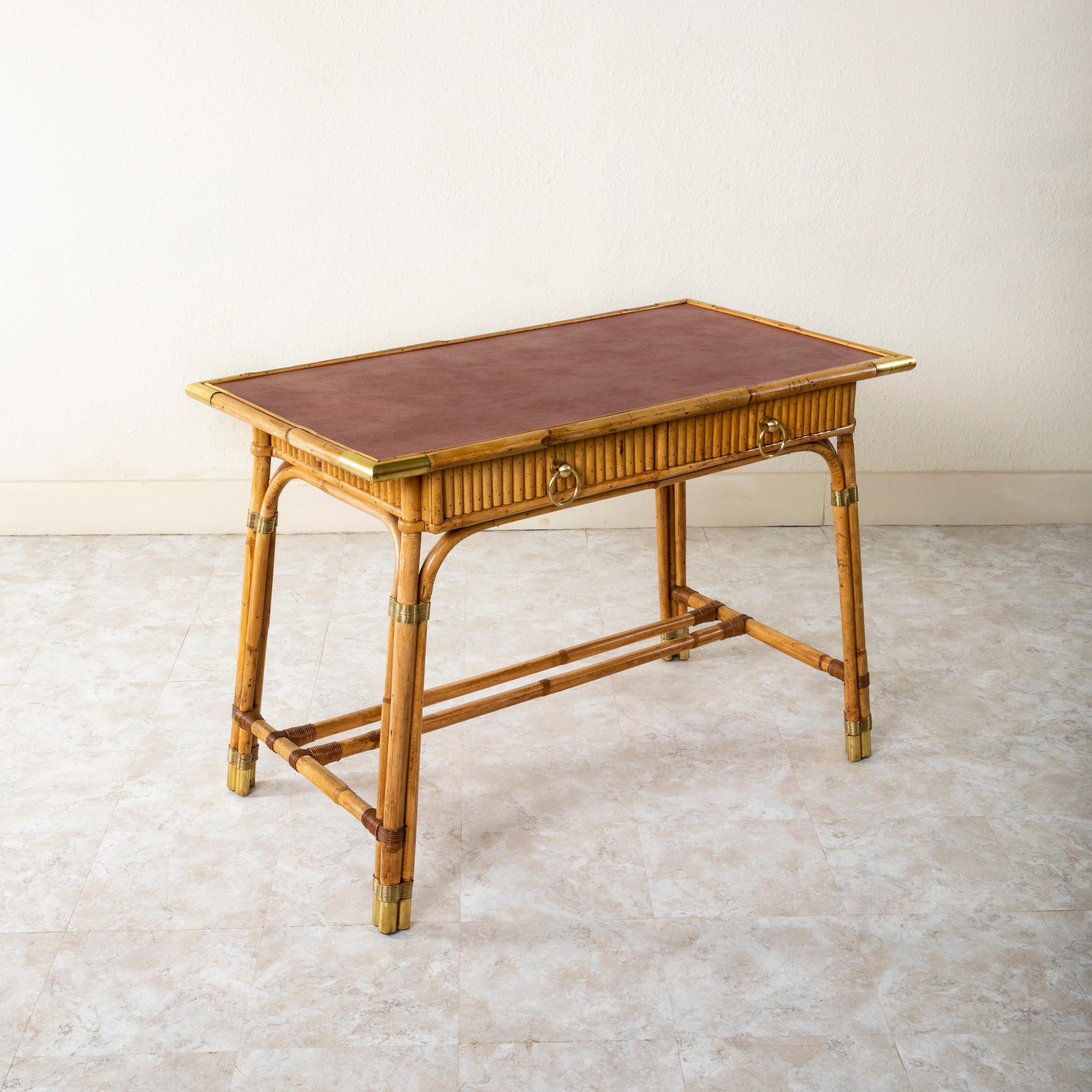 Attribué à Louis Sognot (1892-1970), designer pour la Maison Jansen, ce bureau ou table à écrire français du milieu du XXe siècle est construit en bambou et comporte un plateau en cuir rouge. Les coins autour du plateau et des pieds sont tous