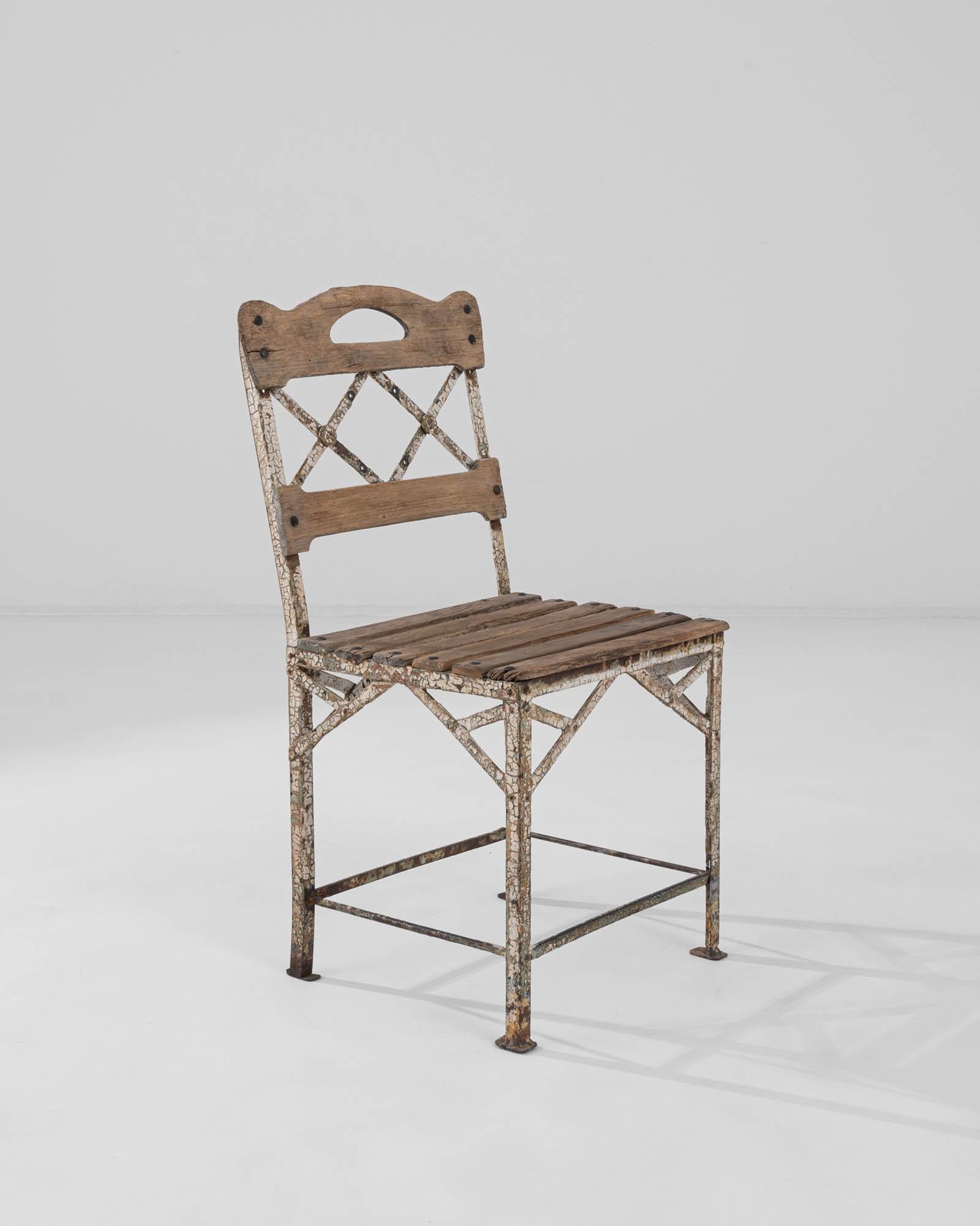 A wooden and metal chair created in 20th century France. Weathered and cracked through time, this chair retains its original dignity with a kind of maturity only earned through the years. The criss-crossing bands of metal that compose its structure