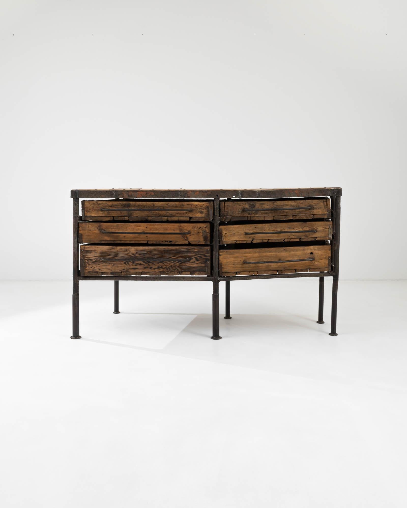 A wooden and metal work table created in 20th century France. A rag tag collection of patinated wooden drawers, secured by banded strips of iron line the sturdy industrial frame. Weathered wood and exposed welded metal joinery exudes this work