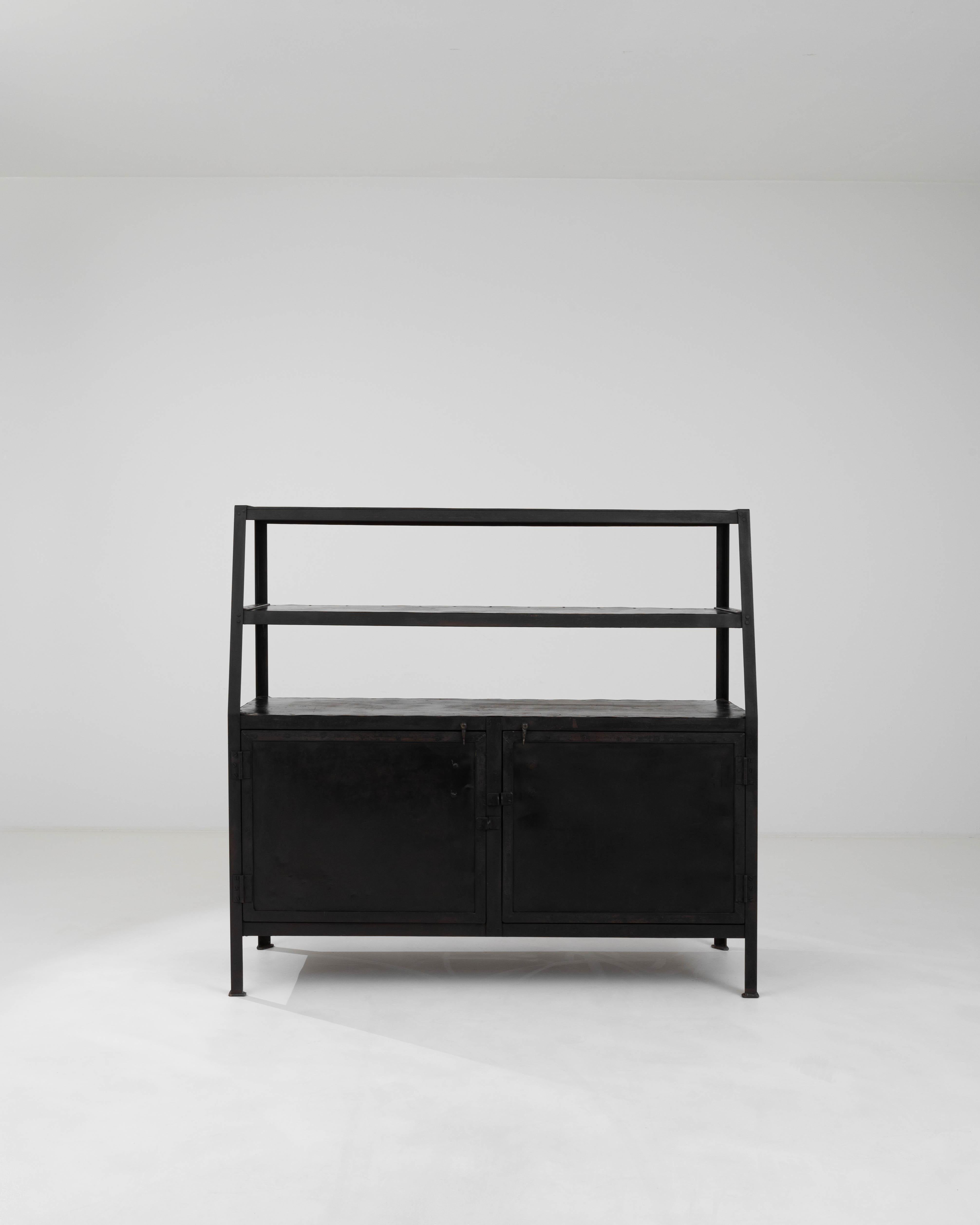 Step into an era of industrial chic with this 20th Century French Metal Cabinet, a sturdy and striking addition to any modern loft or traditional space seeking a touch of raw elegance. This multifaceted piece boasts a clean, black metal finish,