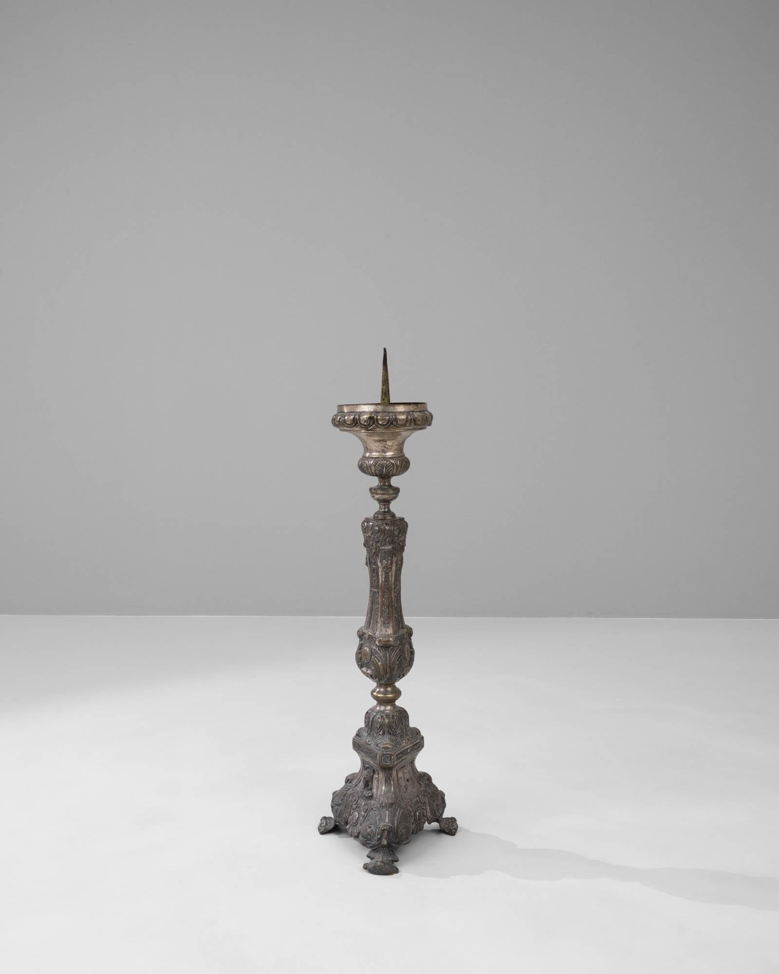 This 20th-century French metal candlestick is an exquisite piece of decor, steeped in ornamental beauty and classic charm. The intricate detailing on its shaft and base reflects the grandeur of Baroque design, with flourishes and curlicues that