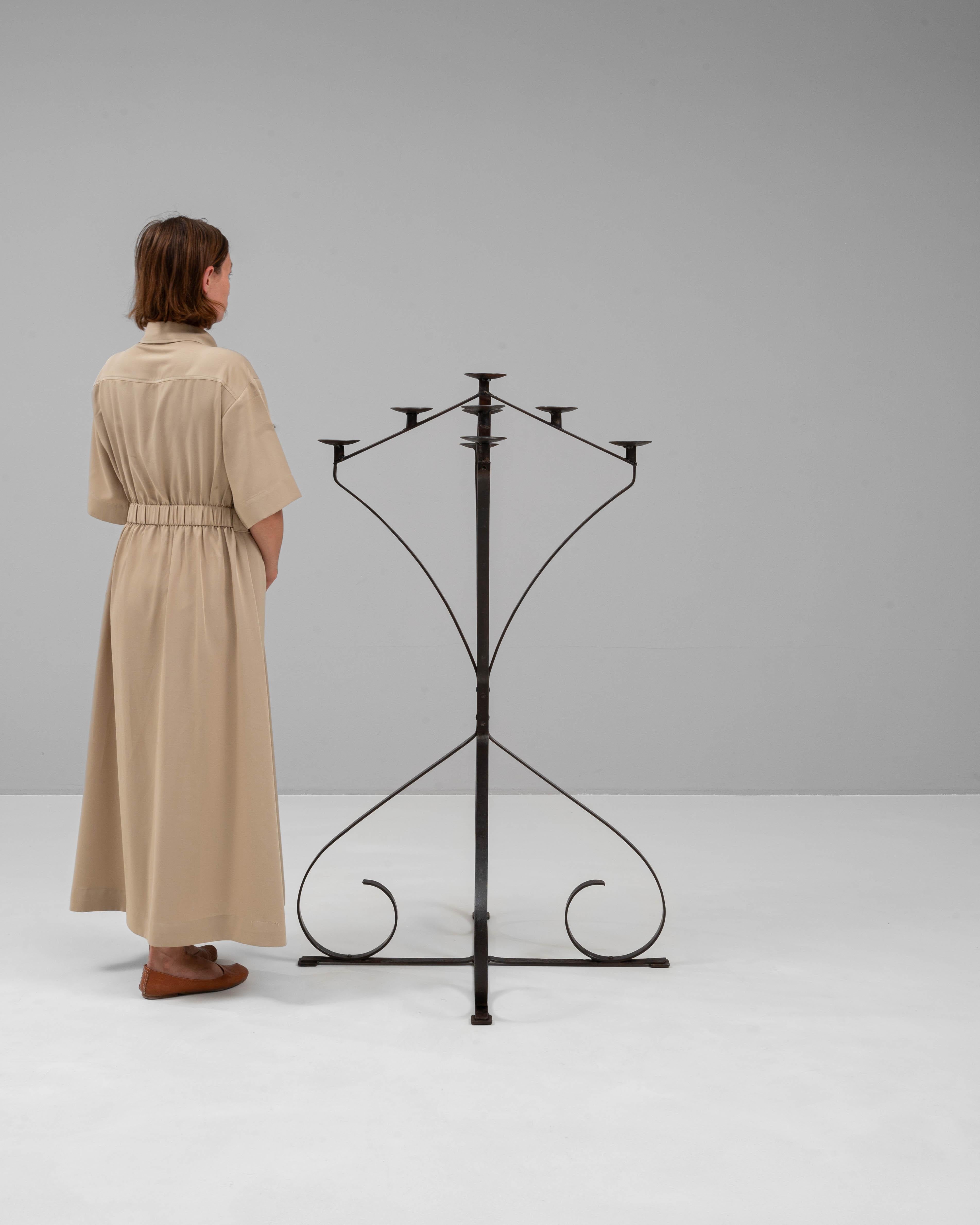 Questo candeliere francese in metallo del XX secolo emana un fascino elegante e rustico. Con una struttura in ferro minimalista ma sofisticata, questo pezzo è progettato per contenere più candele, creando un punto focale straordinario per qualsiasi