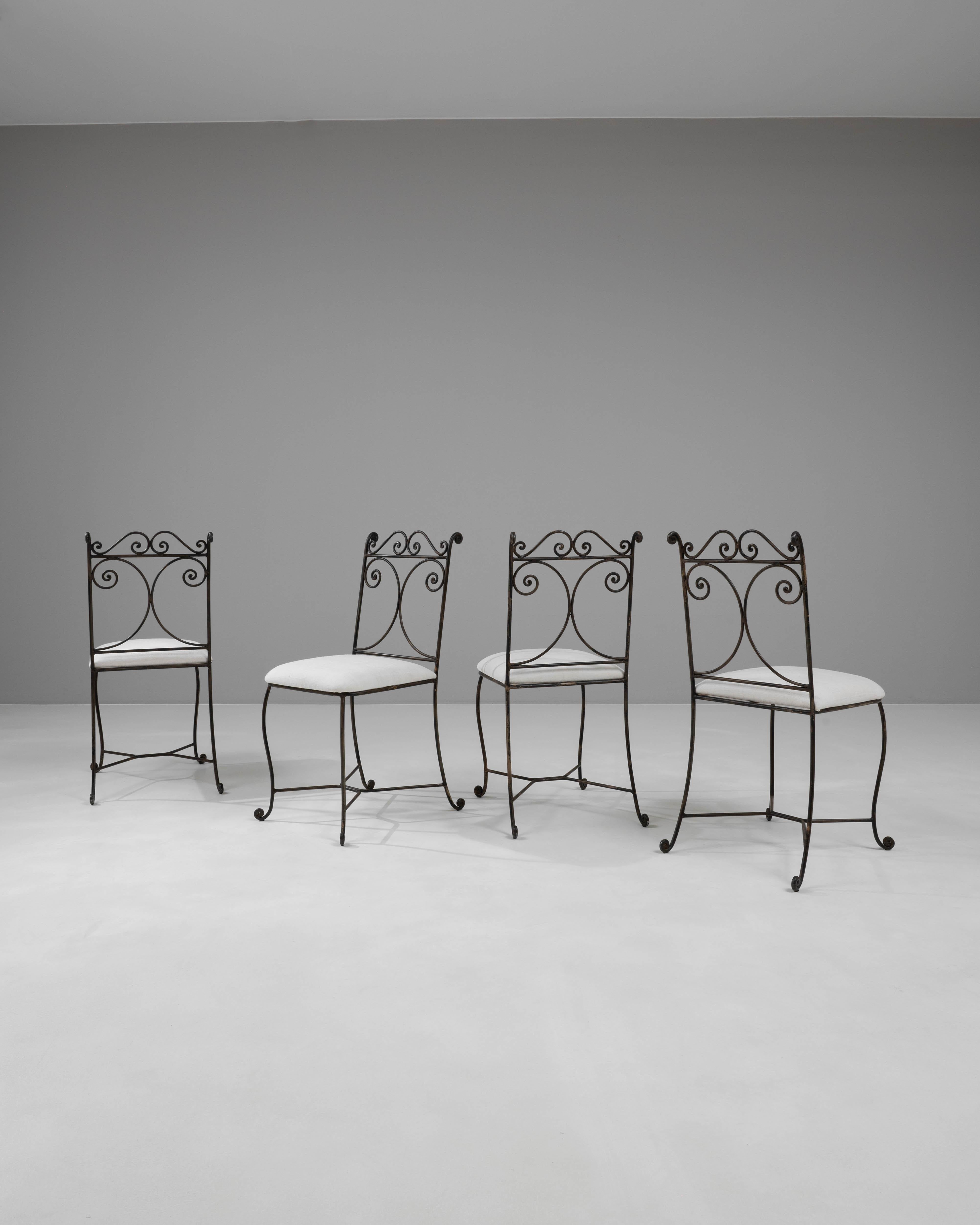 This elegant set of four 20th Century French Metal Chairs offers a beautiful blend of classical design and industrial flair, perfect for adding a unique touch to any dining room or patio setting. Crafted with delicate ironwork, the chairs feature