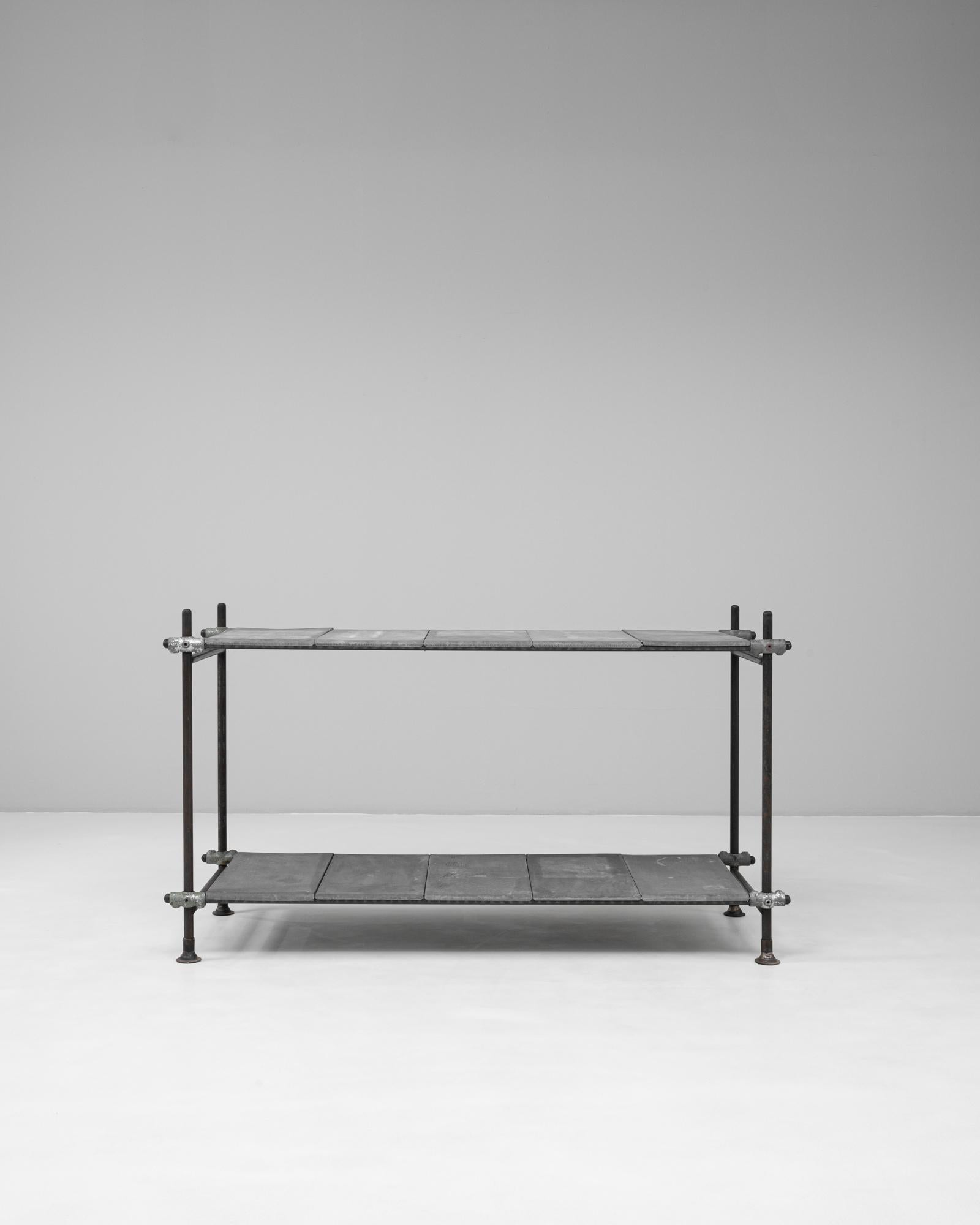 Questa consolle industriale francese del XX secolo presenta un design minimalista e utilitaristico dal carattere grezzo. Realizzato con una robusta struttura in metallo e due ripiani rivestiti in zinco, incarna la raffinata semplicità dei primi