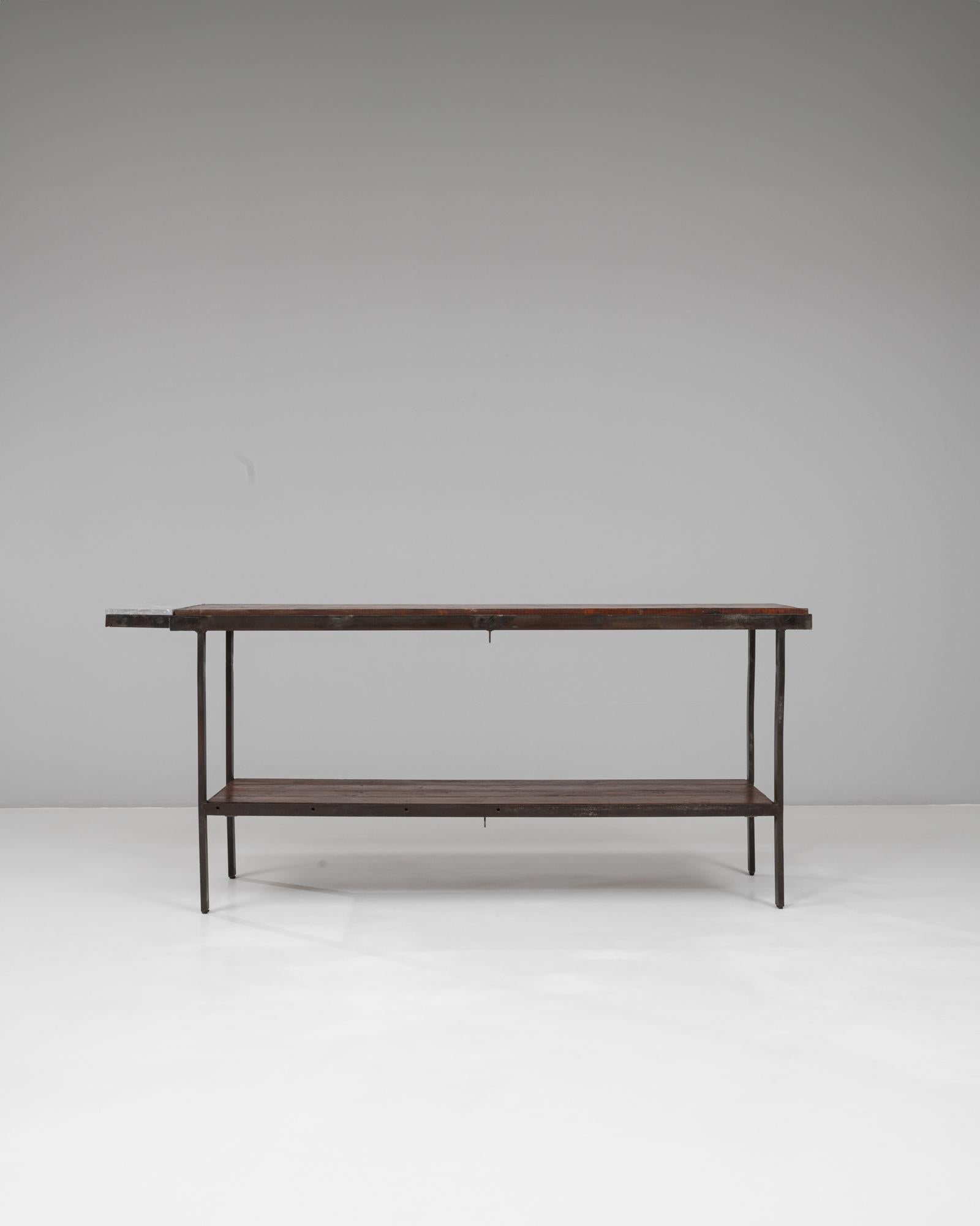 Cette table industrielle française du XXe siècle incarne le design utilitaire avec une élégance discrète. Fabriqué en métal patiné foncé et en bois richement grainé, il présente une longue forme rectangulaire avec une étagère inférieure pour plus de