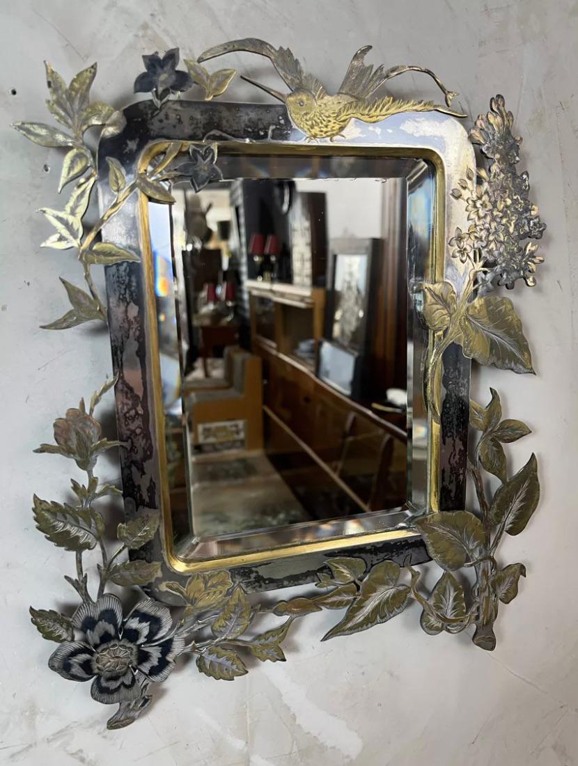 Add a touch of elegance and character to your home with this charming small beveled mirror. Its ornate frame, crafted in repoussé metal and adorned with delicate floral motifs and a graceful bird in flight, makes this a decorative piece full of